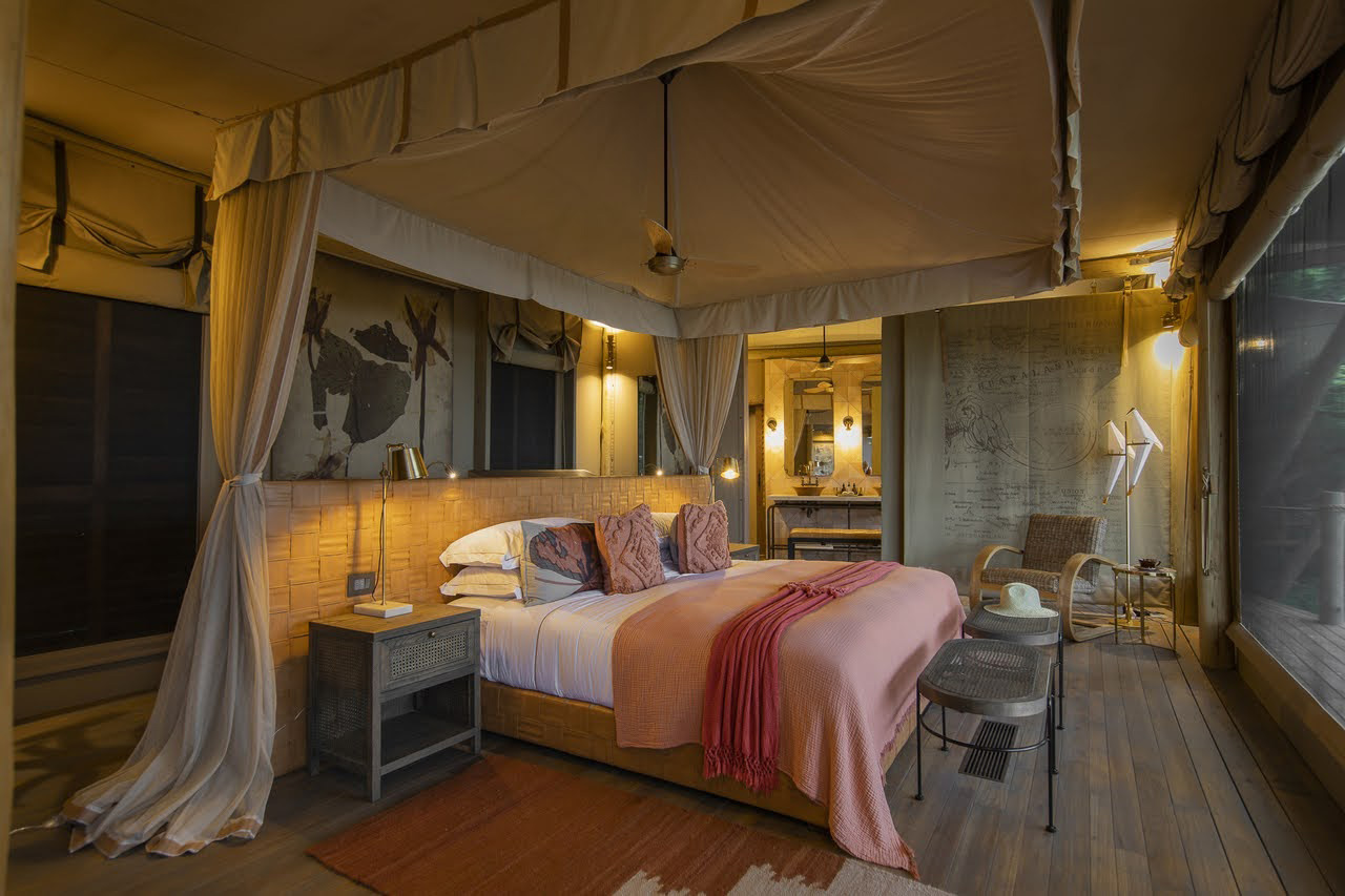 a luxurious safari tent with bed and canopied ceiling