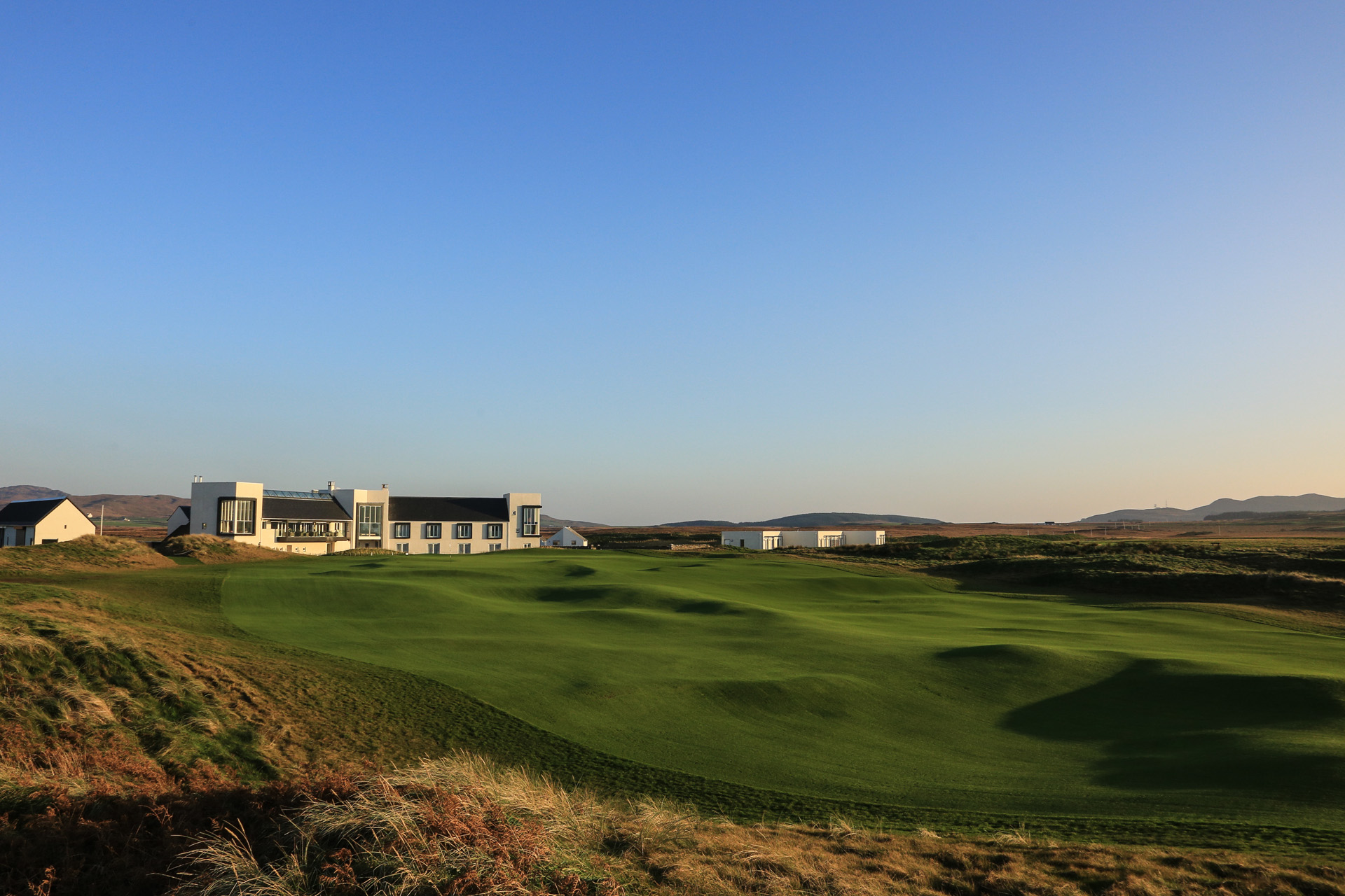 The Machrie exterior, a white hotel against a blue sky and green grass links golf course