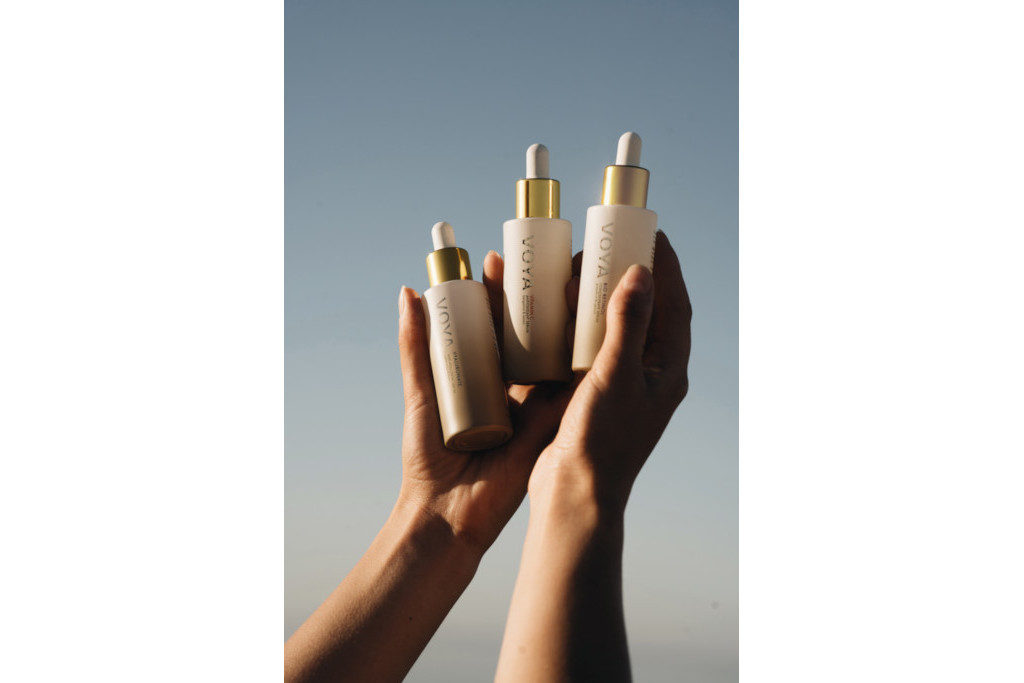 Hands holding three bottles of facial serum
