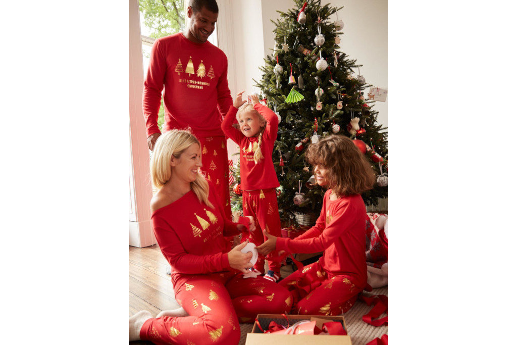 Family in red pyjamas by Christmas tree