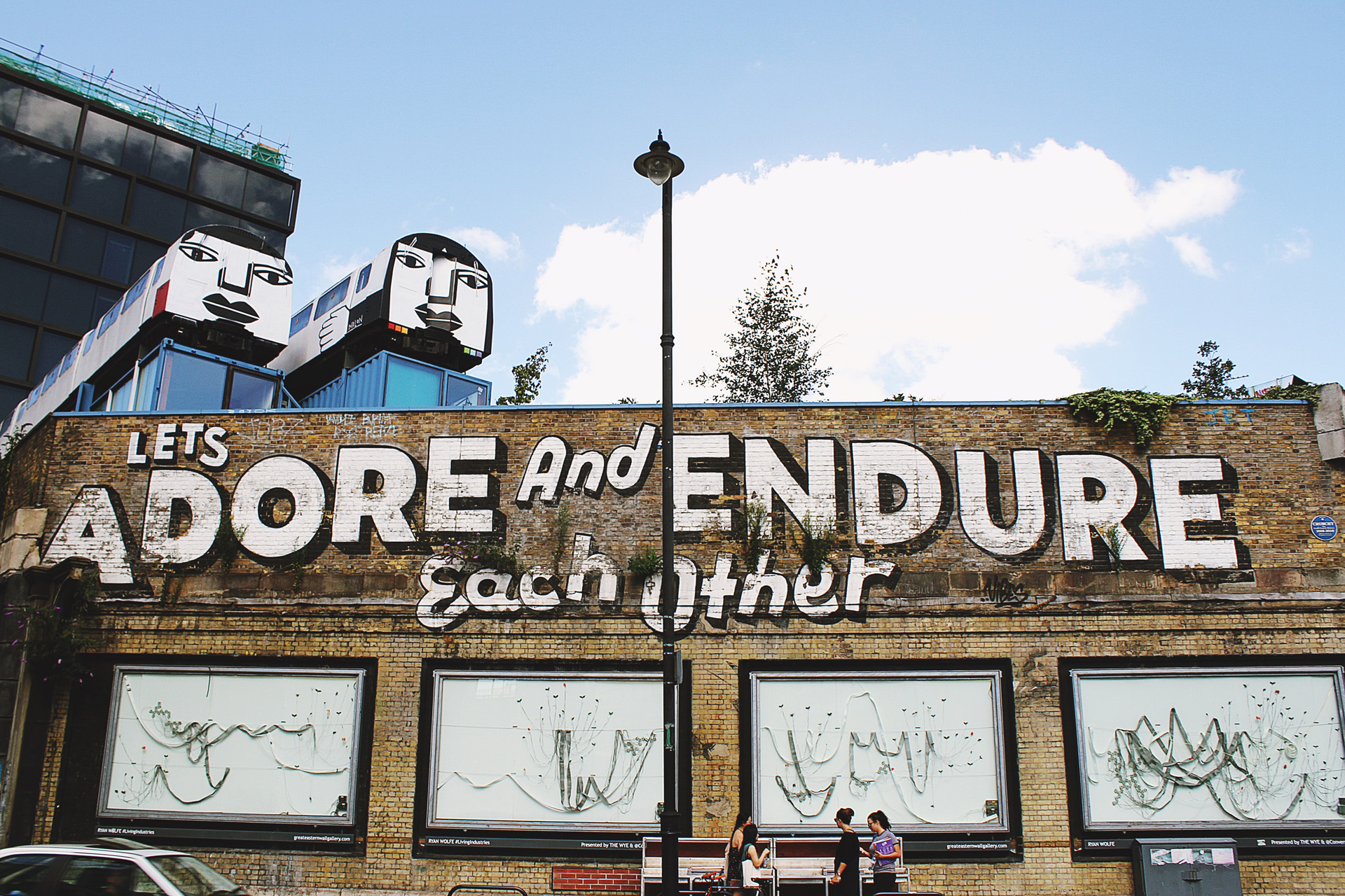 two old trains with painted faces and a mural reading 'let's adore and endure each other'