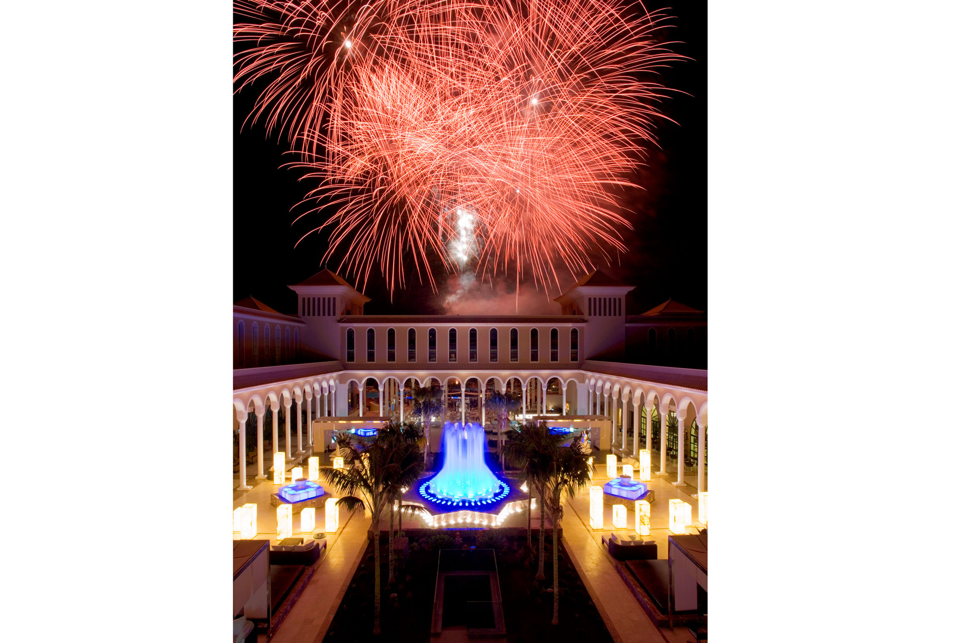 Bright amber coloured fireworks in night sky above hotel