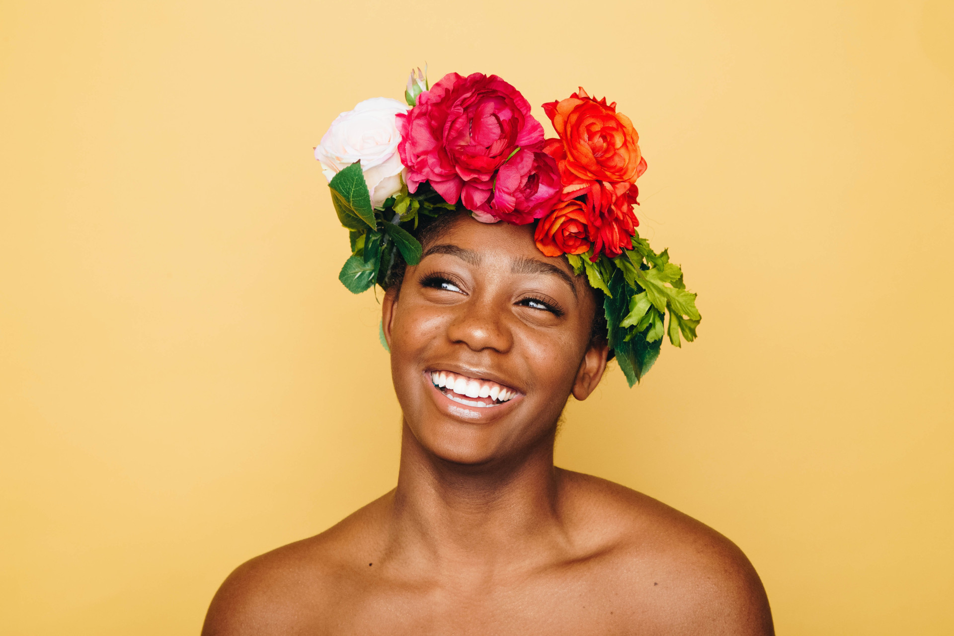 Close up of black woman wearing flower crown on yellow background