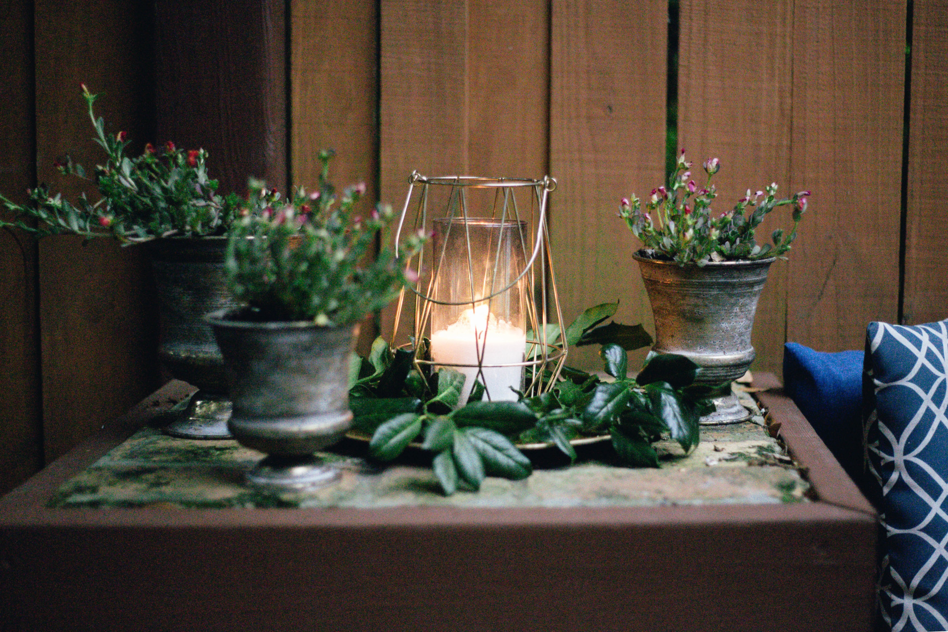 Candle on side table surrounded by plants