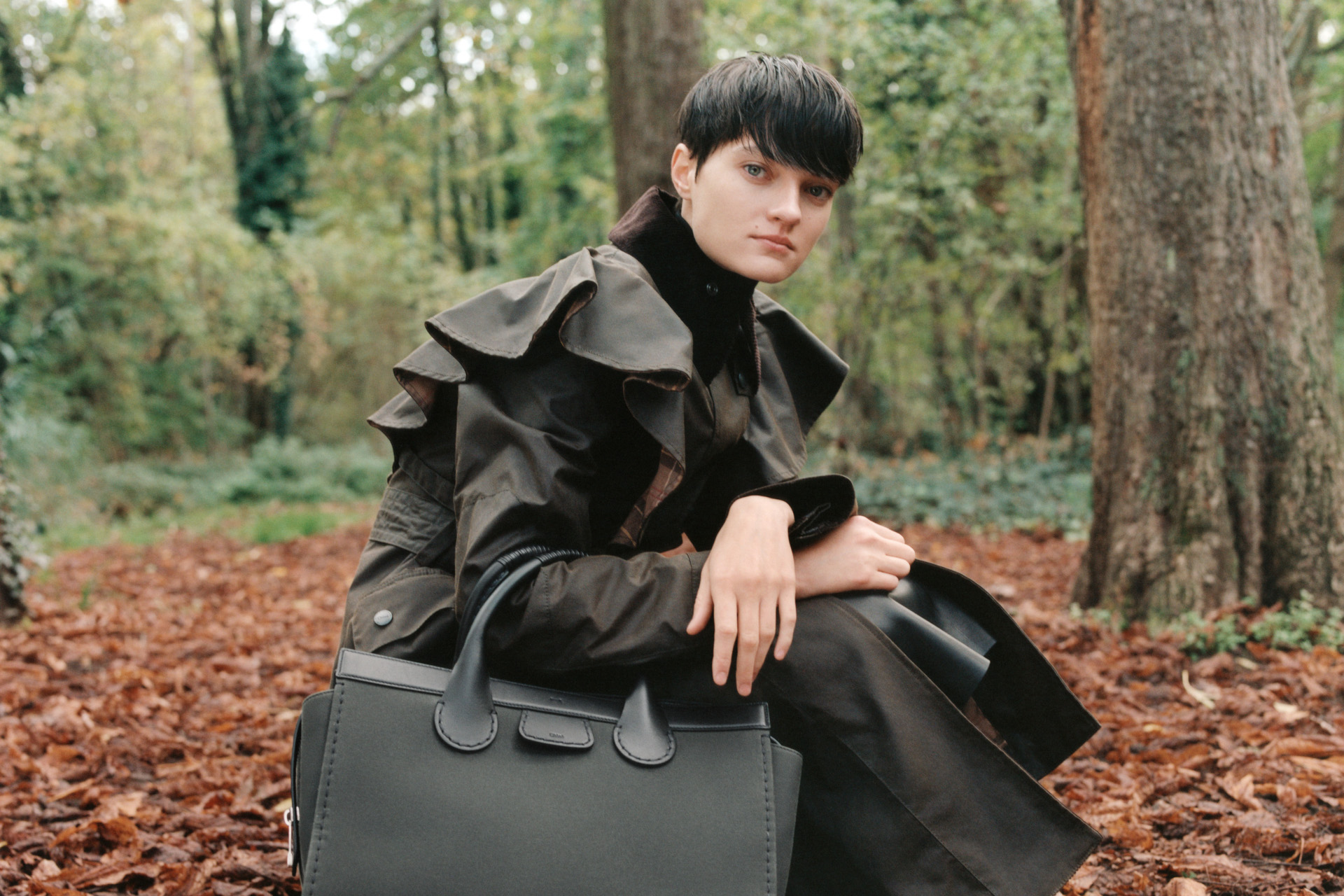 Woman crouched in the woods holding a bag