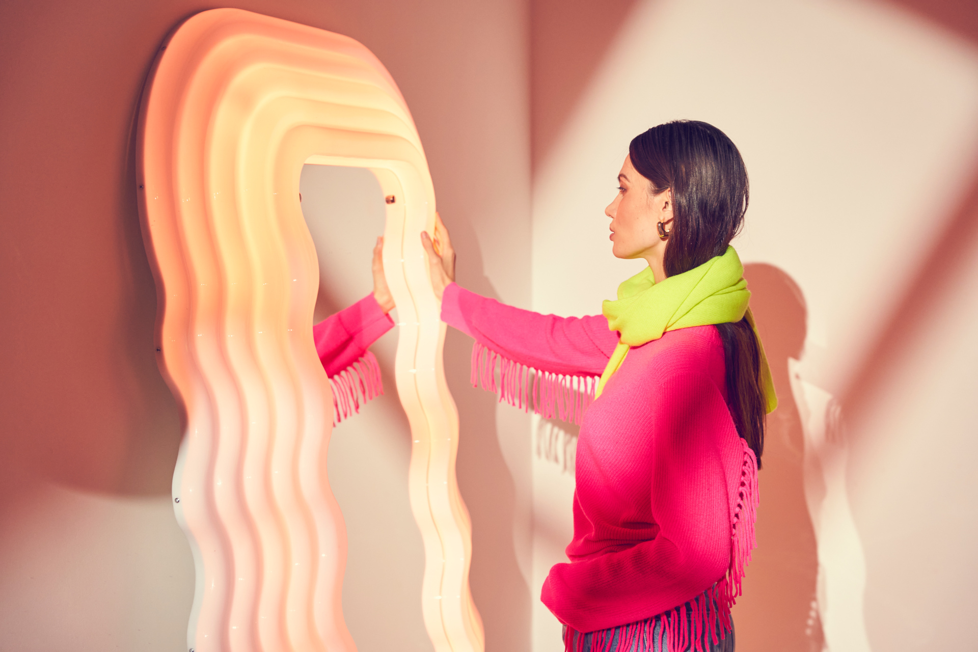 Woman in pink jumper and yellow scarf looking in mirror