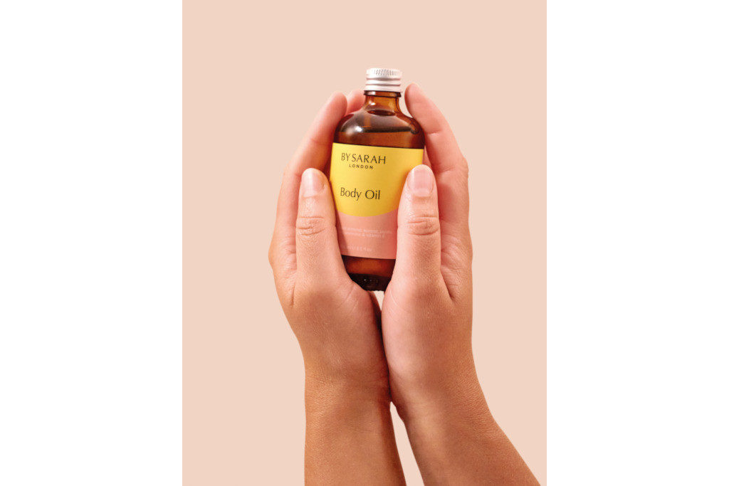 Hands holding a bottle in front of pink background