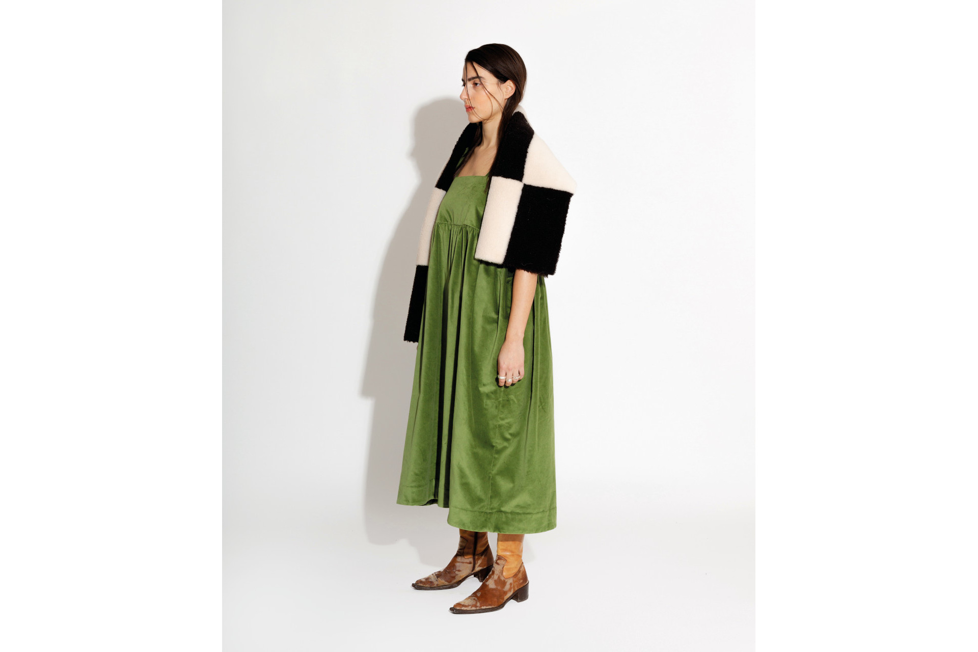 Woman stood in green dress and black and white check scarf
