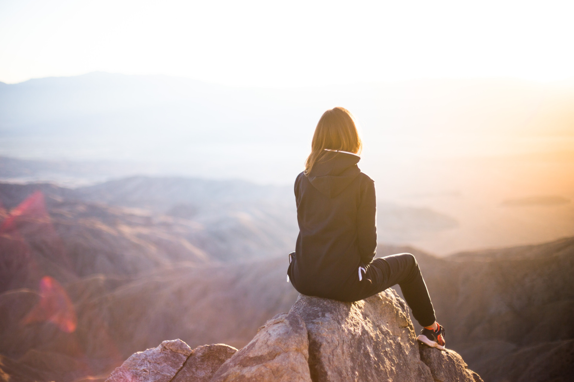 Woman sitting on rocks overlooking hills and mountains