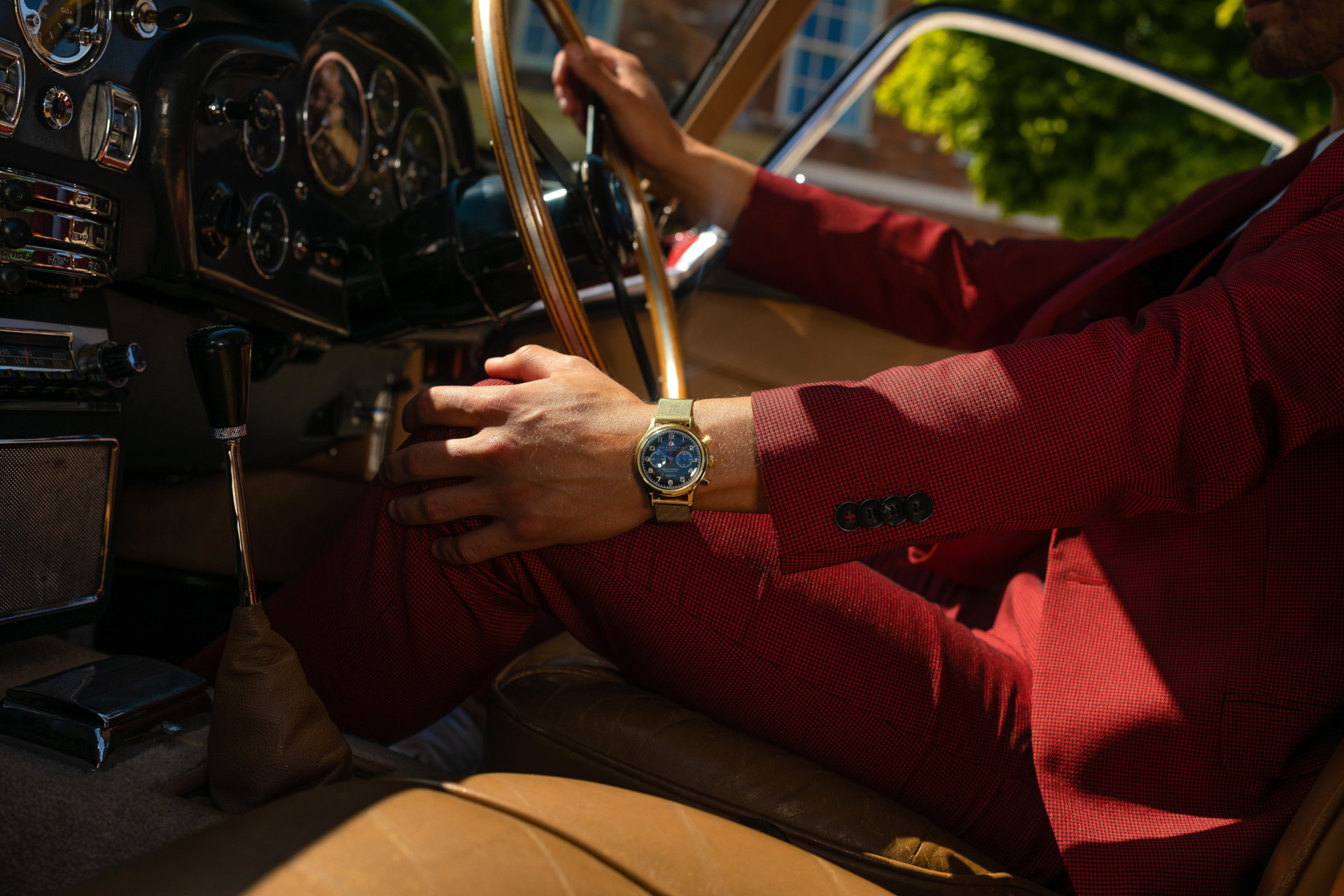 Close up of man driving while wearing a watch and red suit