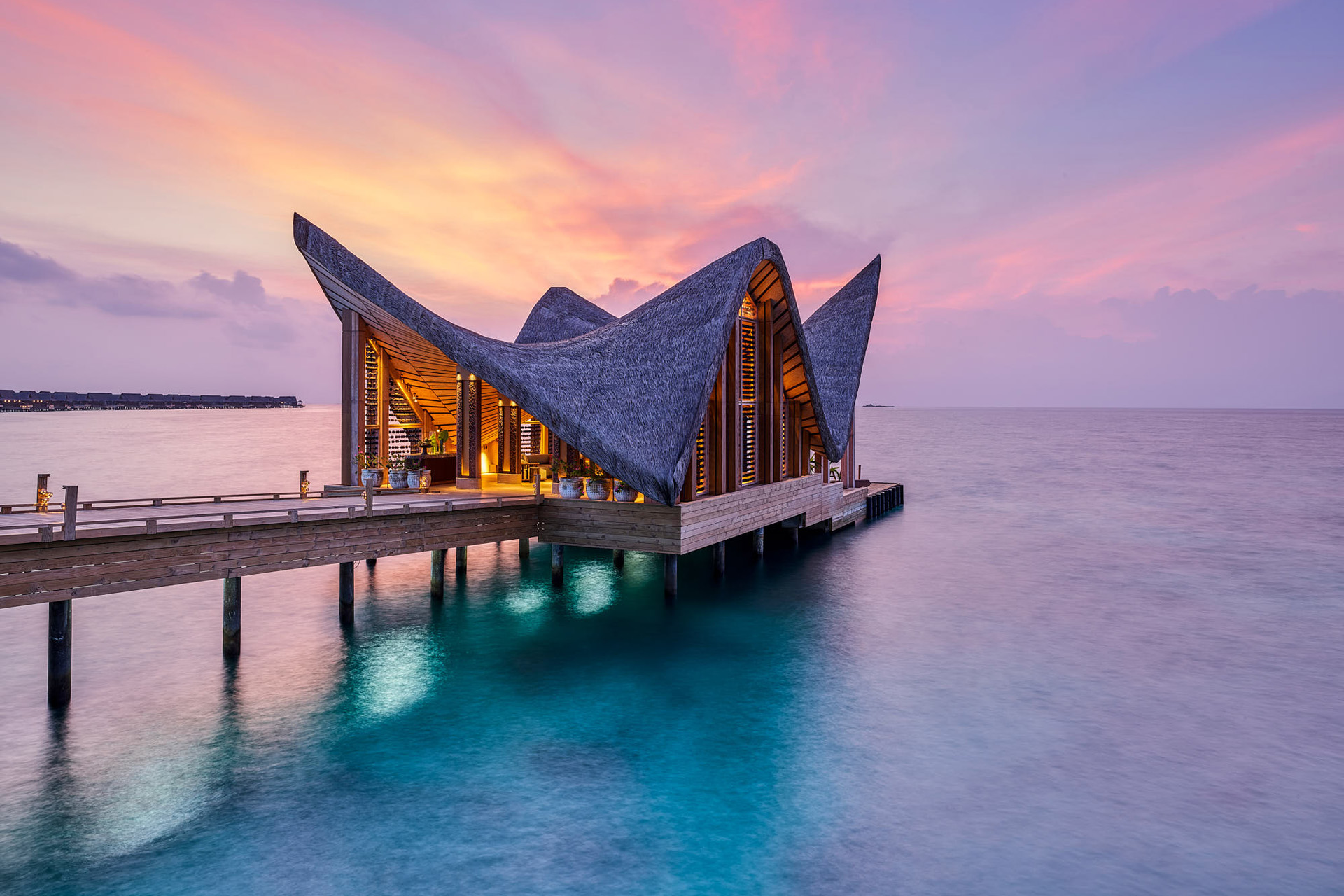 a maldives villa against a purple sunset
