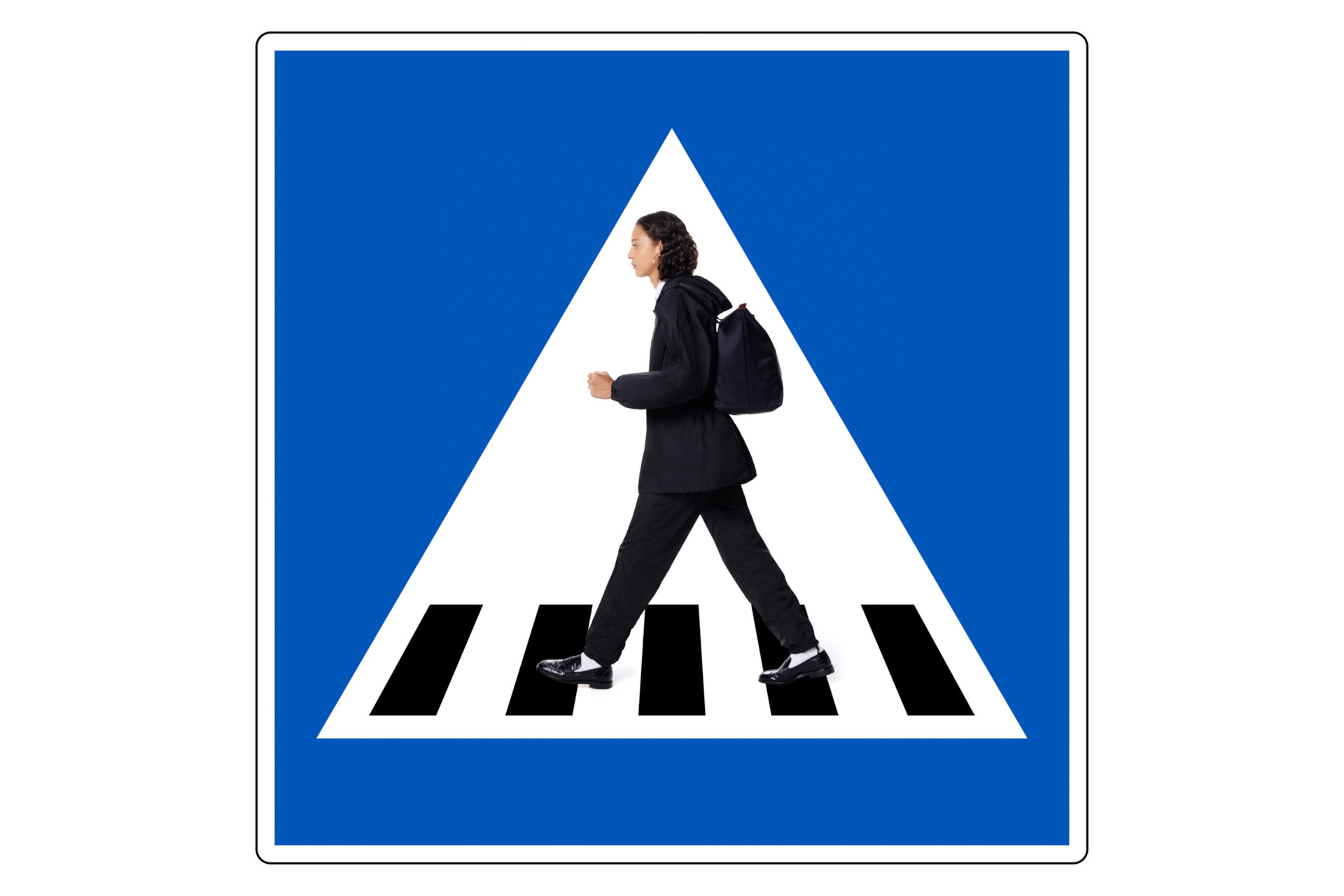 Model in black walking on crossing sign