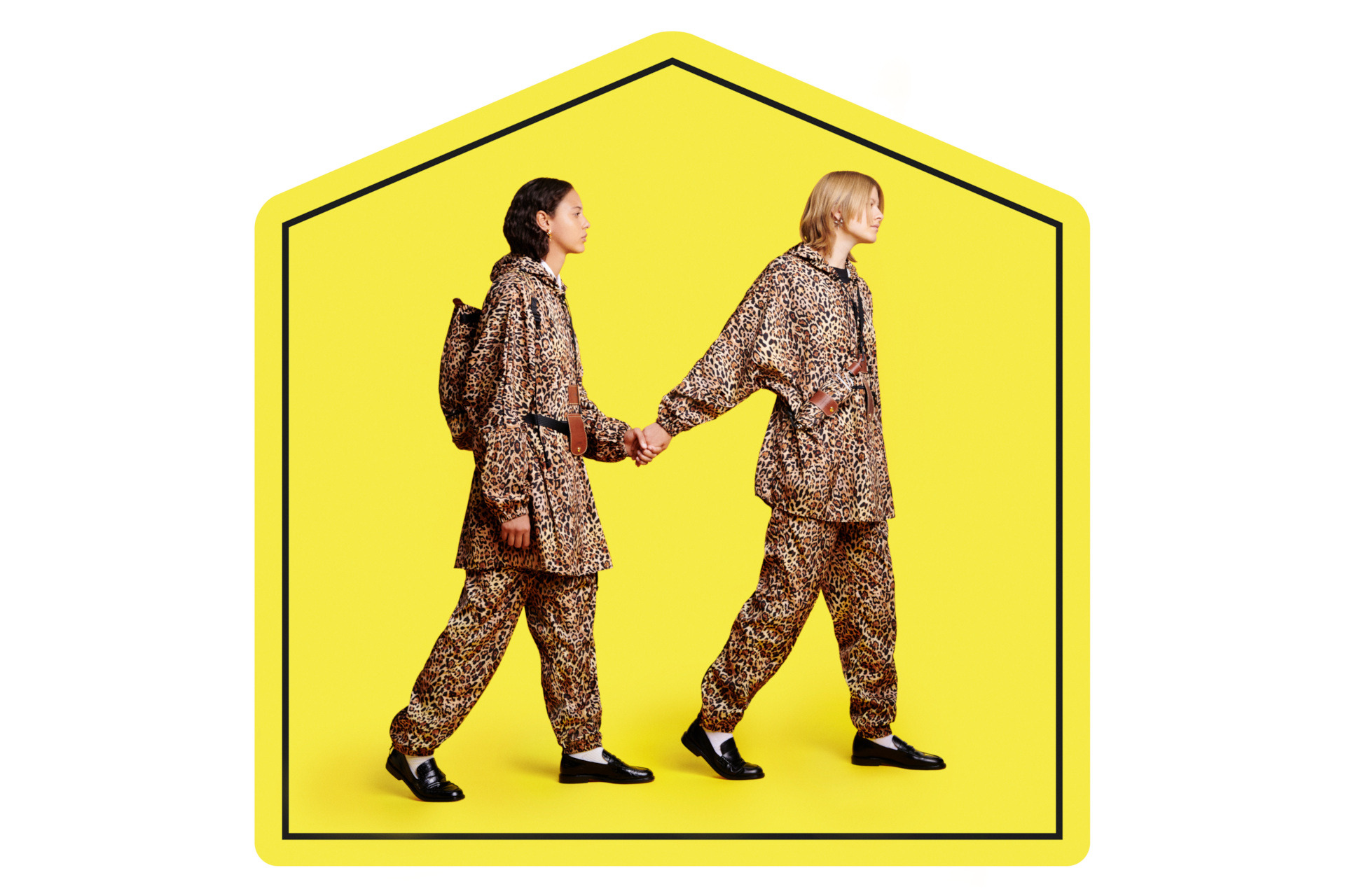Two people holding hands as they walk on a yellow sign