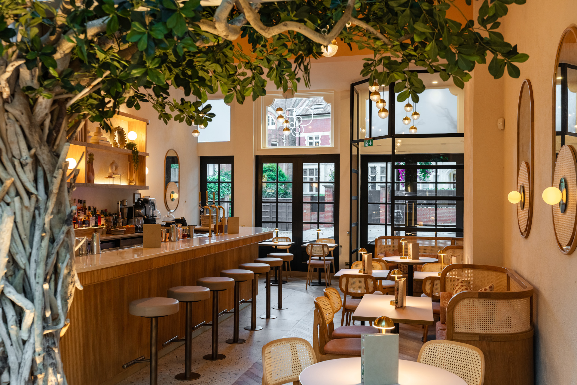 Oak & poppy restaurant and bar interior with trees and warm lighting