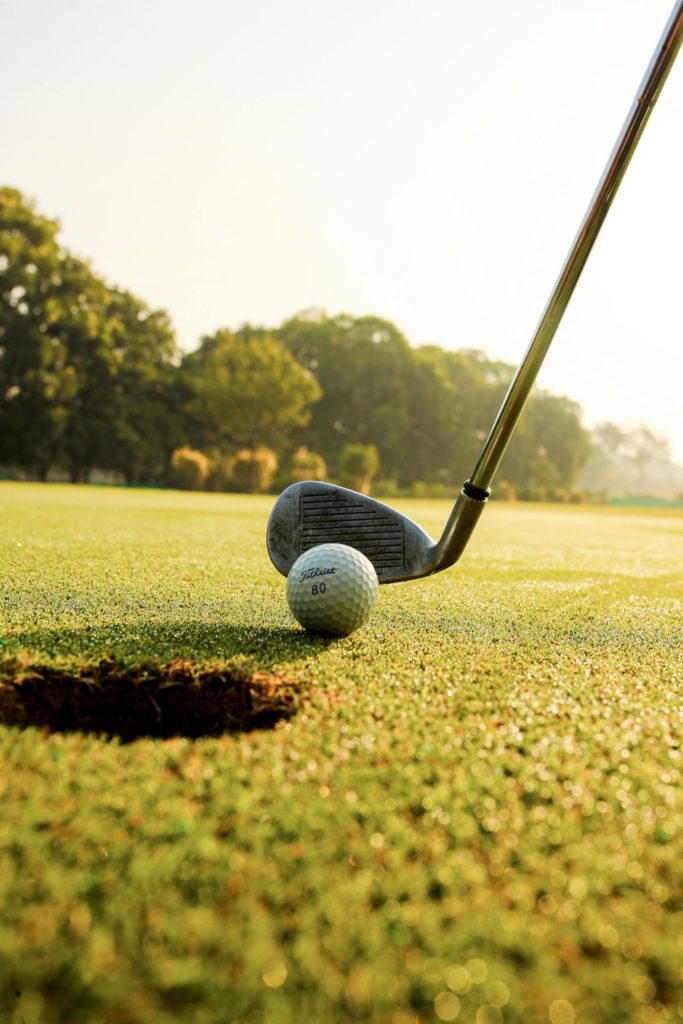 Golf club hitting ball on field