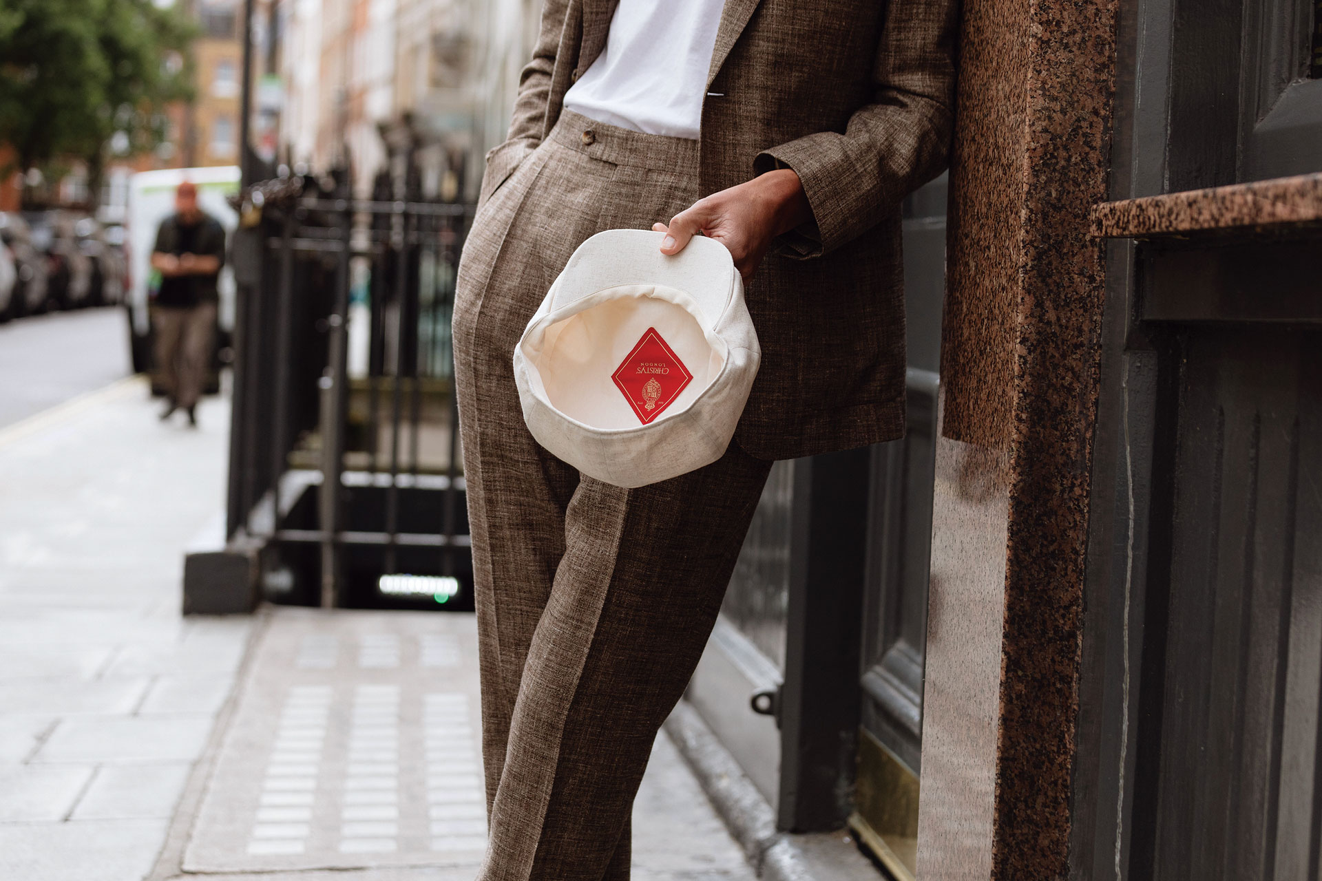 Man, pictured from the stomach down wearing tailored trousers holding Christys' hat