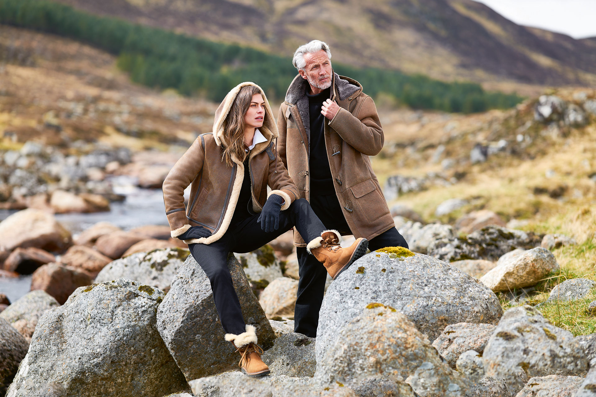 A man and a woman standing by some rocks in the Scottish Highlands