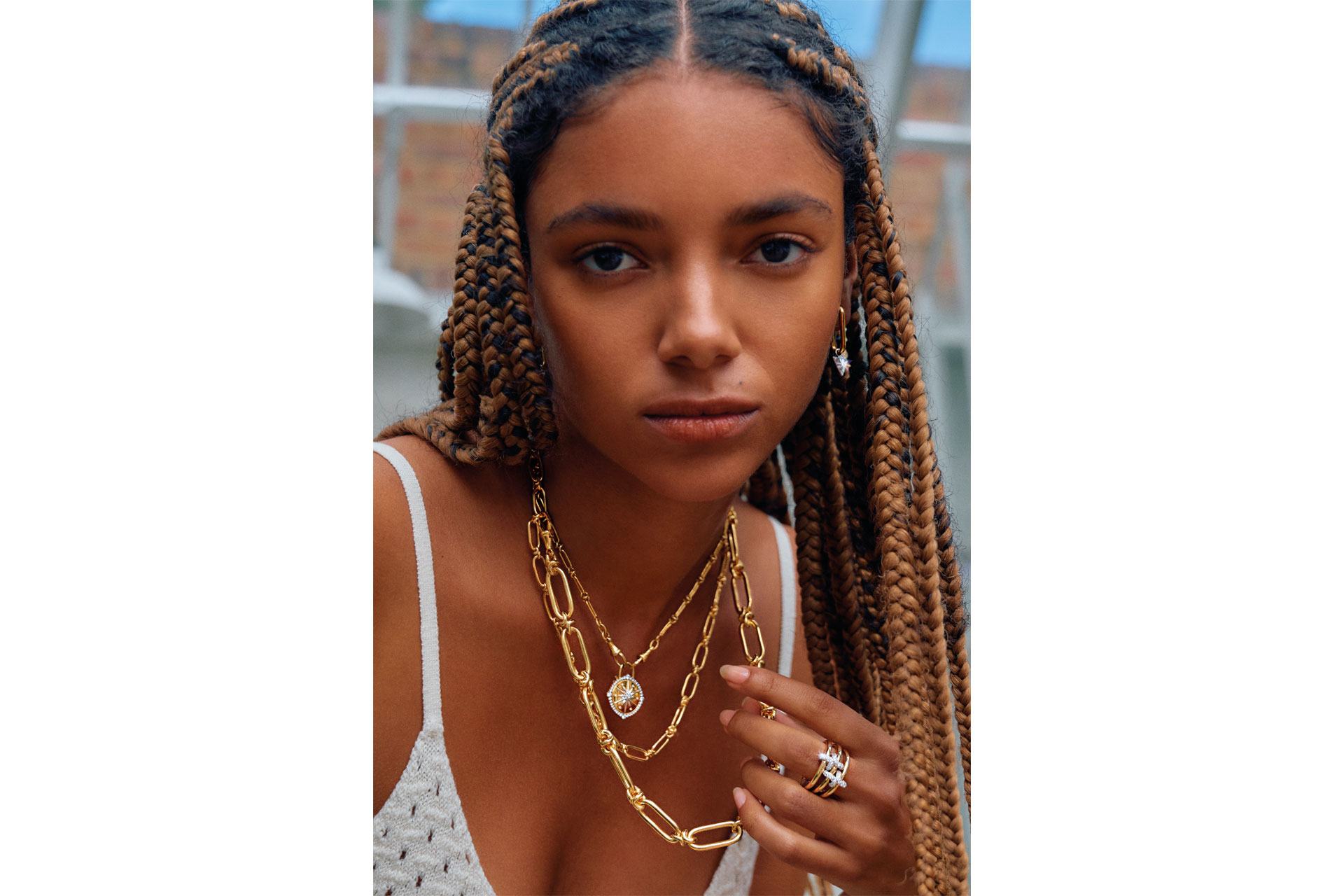 A black model wears a stack of Annoushka necklaces