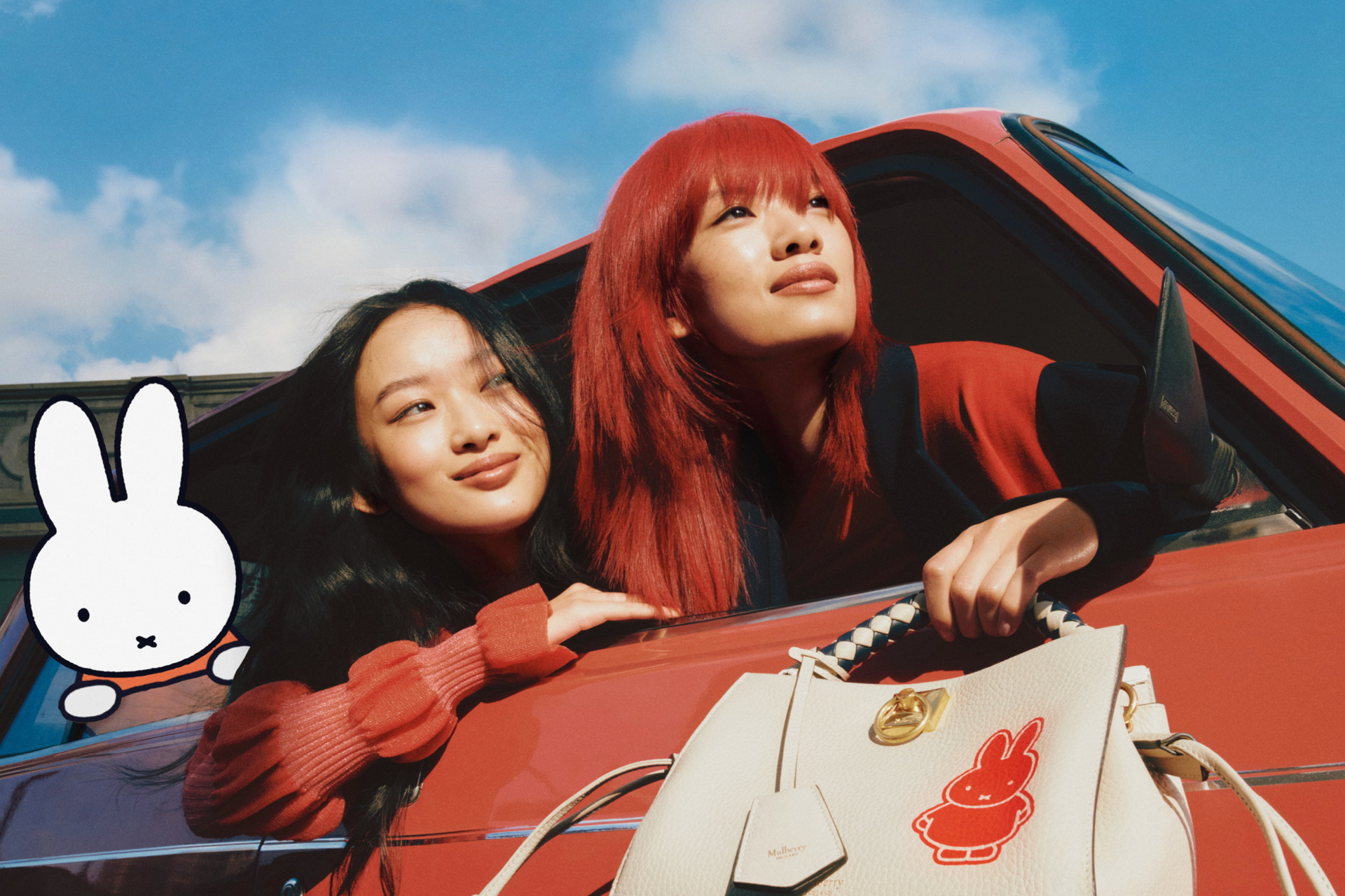 Two girls leaning out of car window beside Miffy character