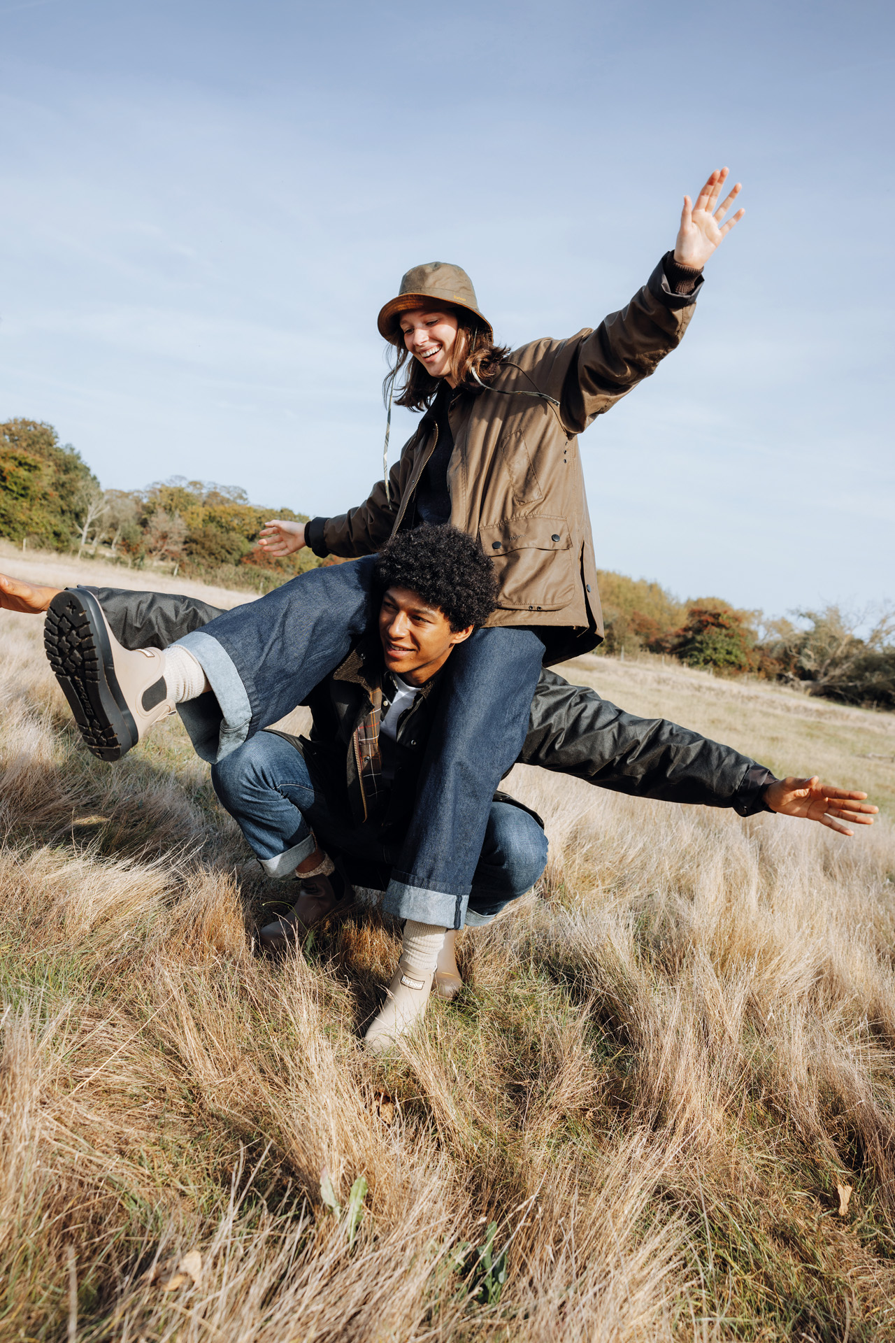 A couple in a hay field dressed in Barbour clothing