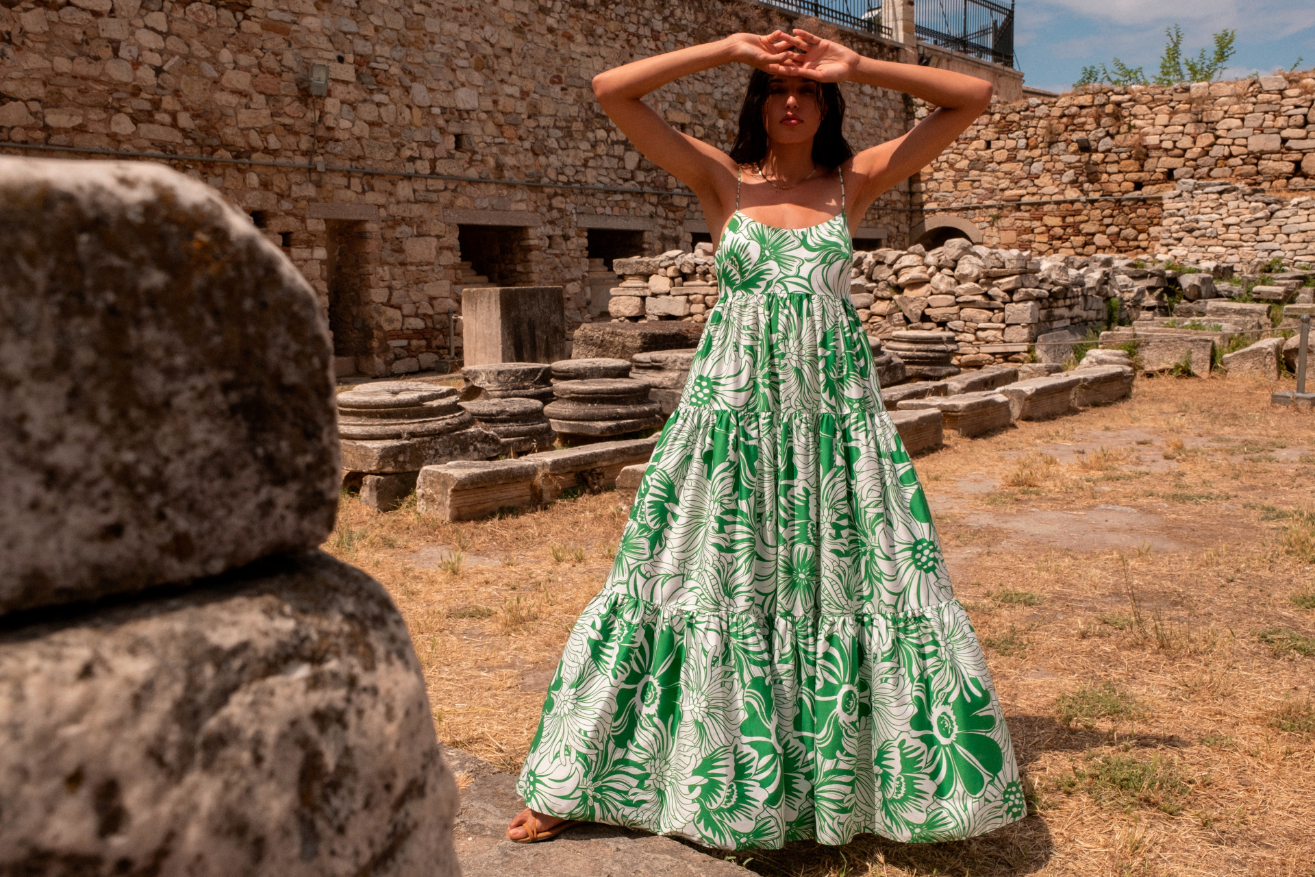 Woman in green floral dress stood in outdoor ruins