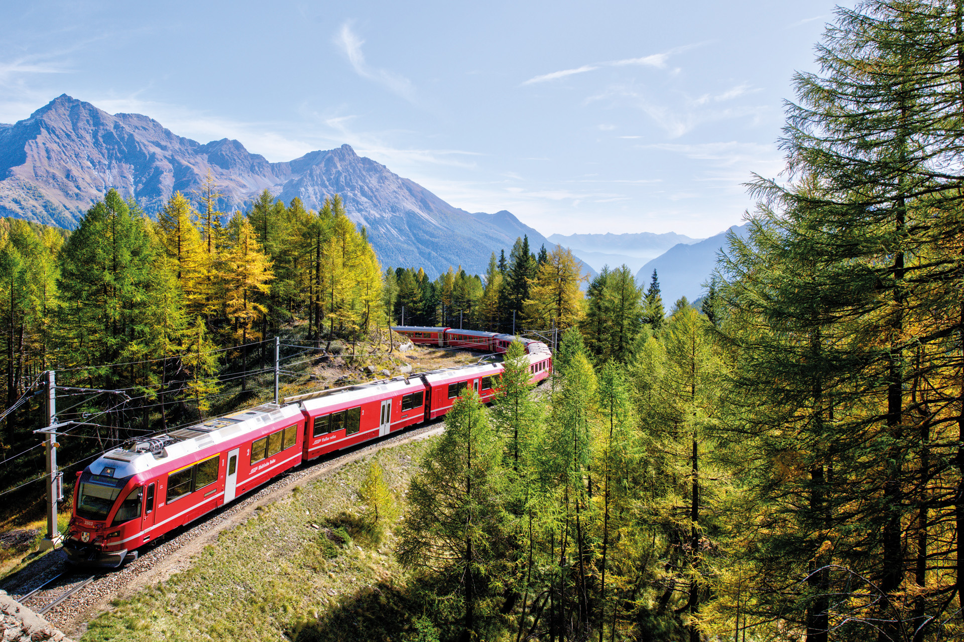 a red train surrounded by trees