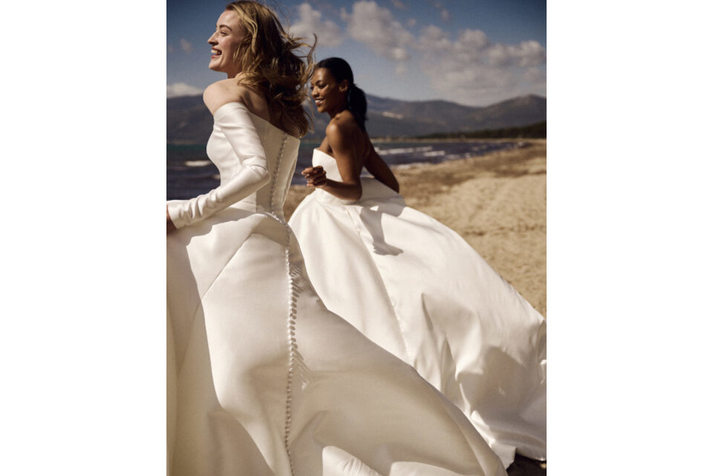 Two women in white dresses on the beach