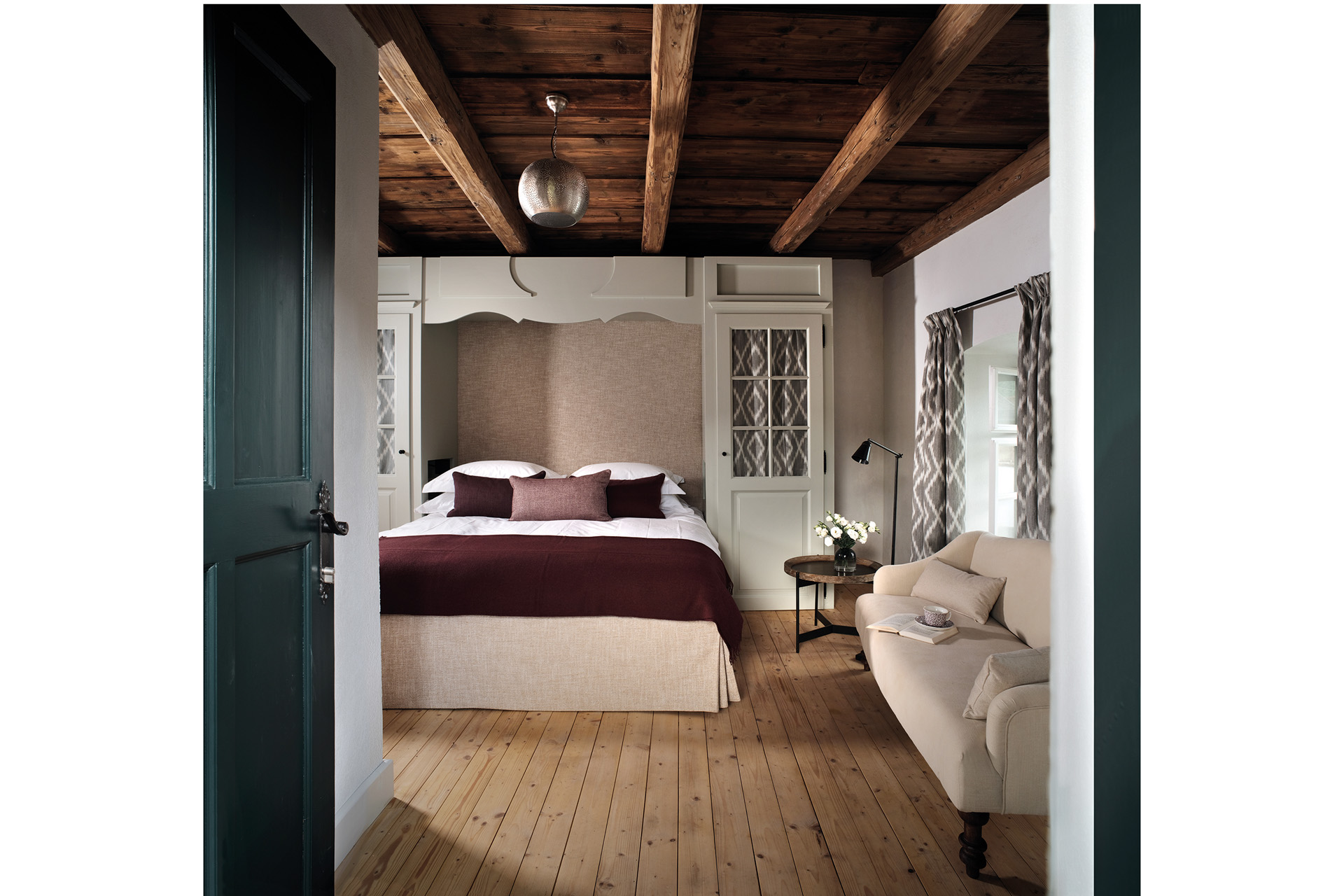 A neutral bedroom with wood beam ceiling