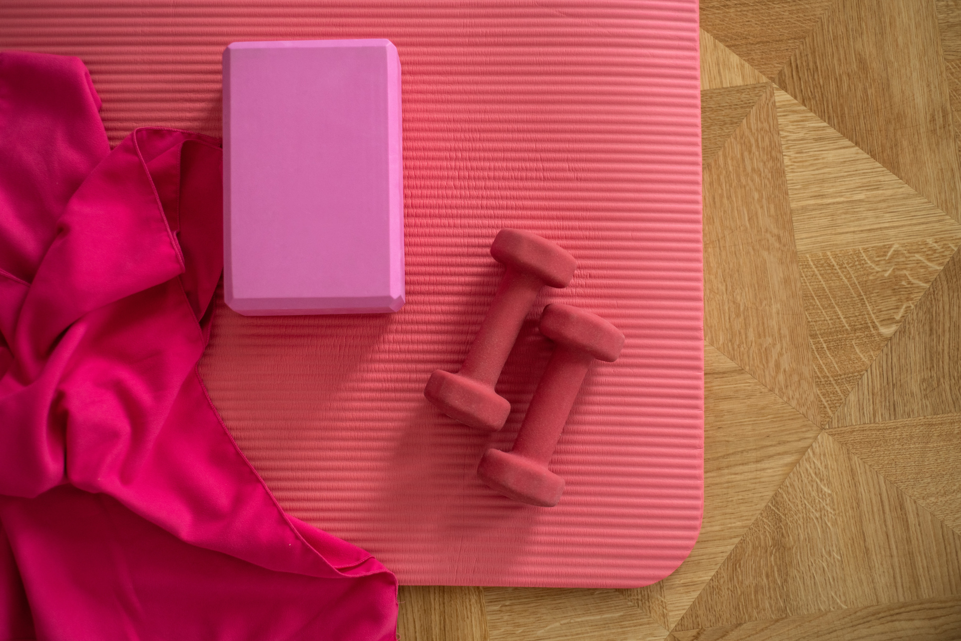 Close up of pink mat and weights on wooden floor