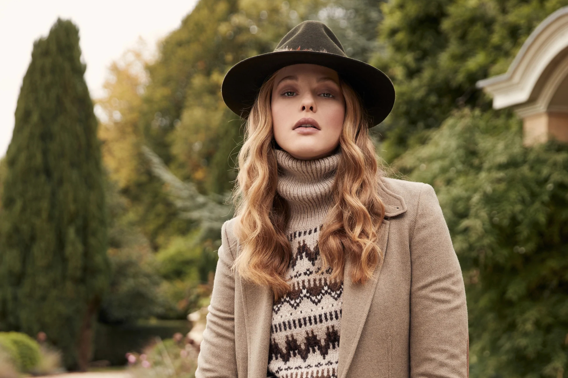 Woman stood outdoors wearing hat, jumper and blazer