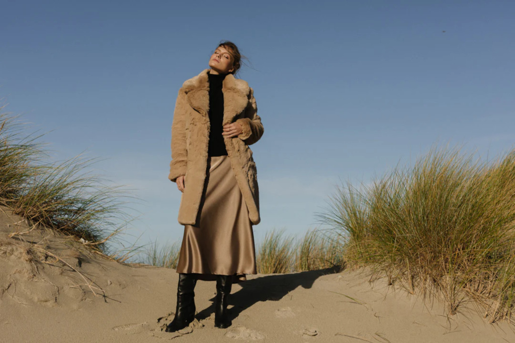 Woman in faux fur coat on beach