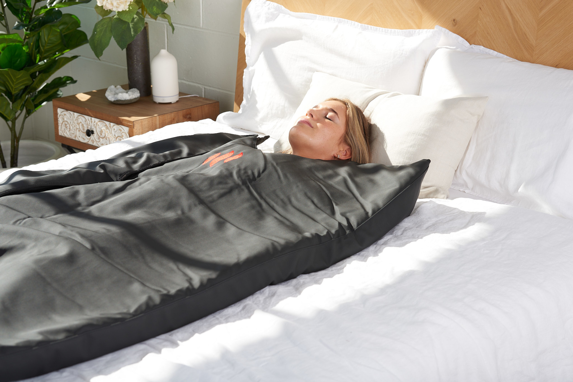 Woman laying down in bed wearing a MiHigh blanket