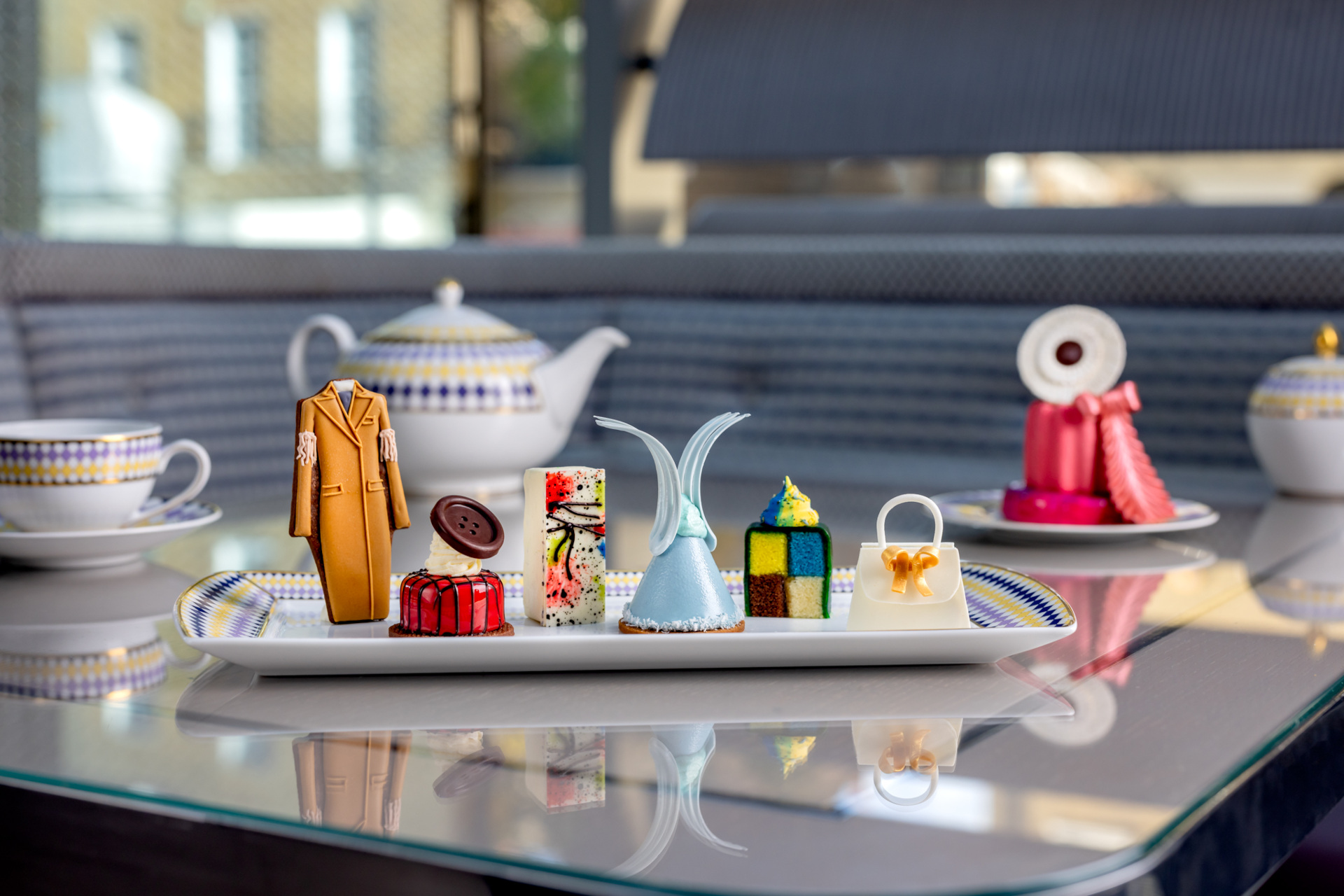 Cakes and biscuits on tray by tea pot