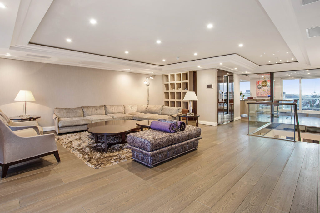 Large living space with wooden floors and large rear windows with a view of a roof terrace space outside
