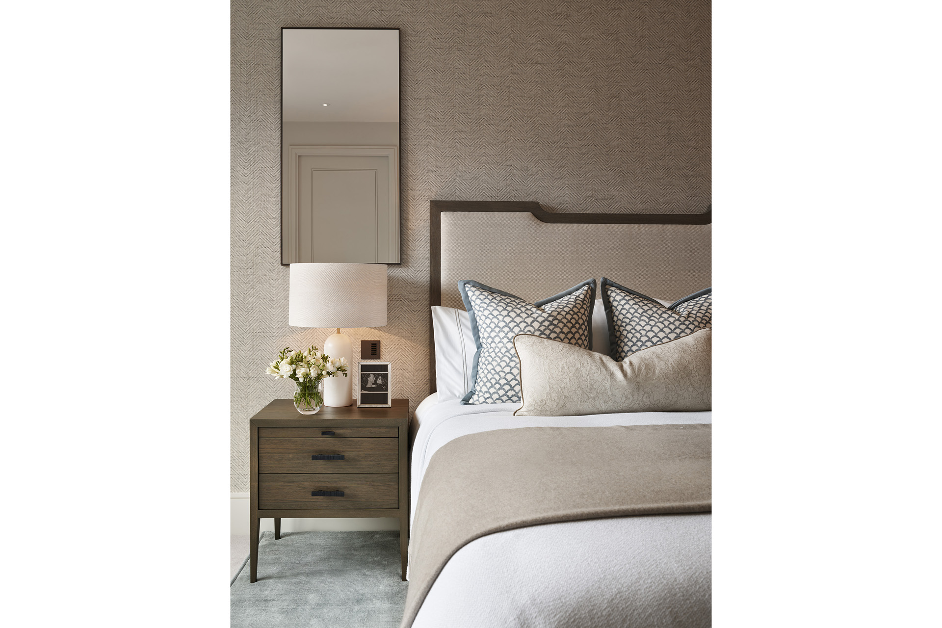 A bedroom with a bed, side table and mirror