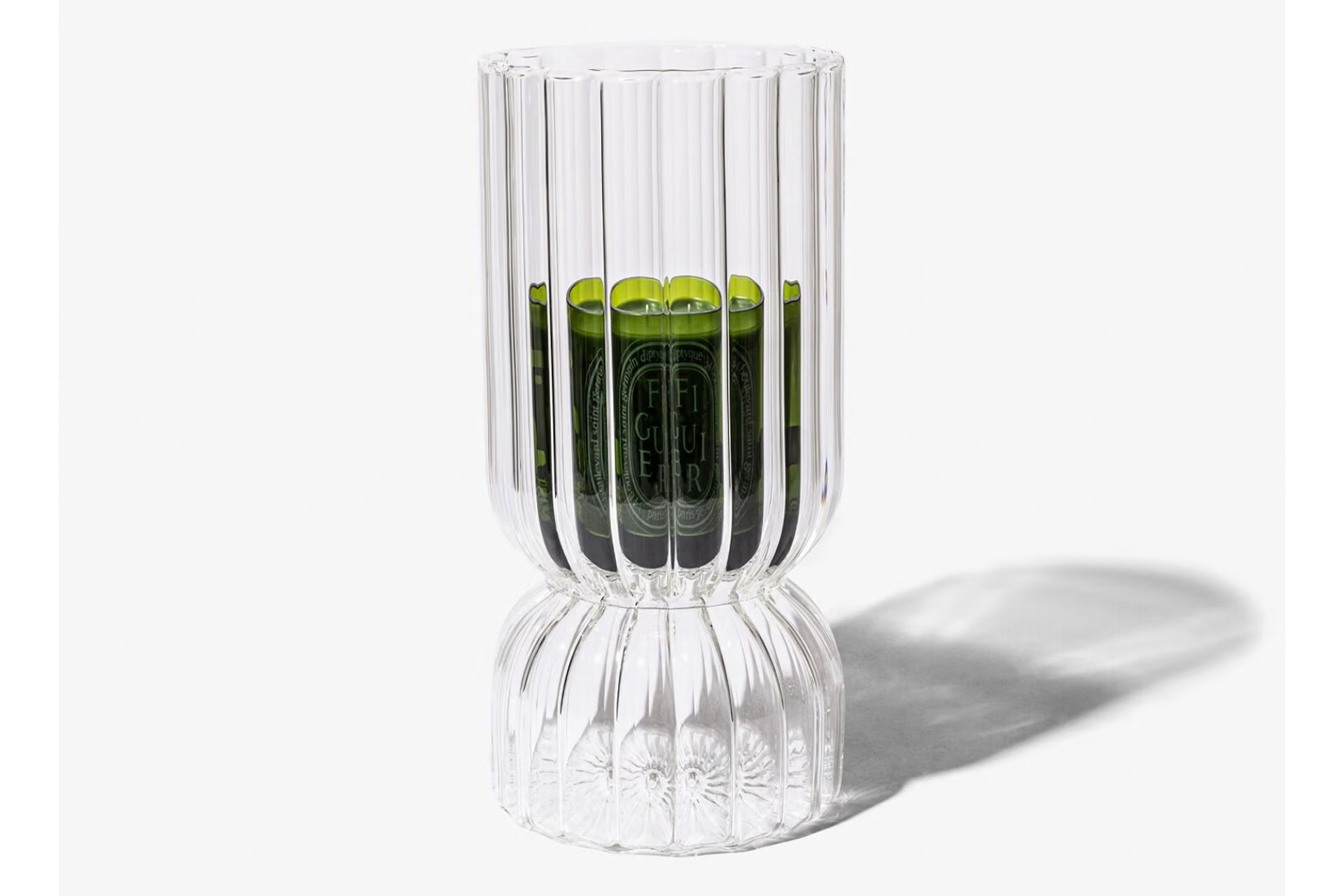 Green Diptyque candle in fluted glass candle holder.
