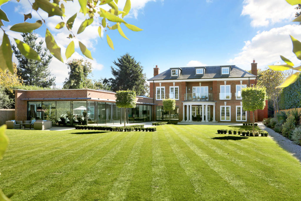 Red brick country house with lawns and glass building with swimming pool