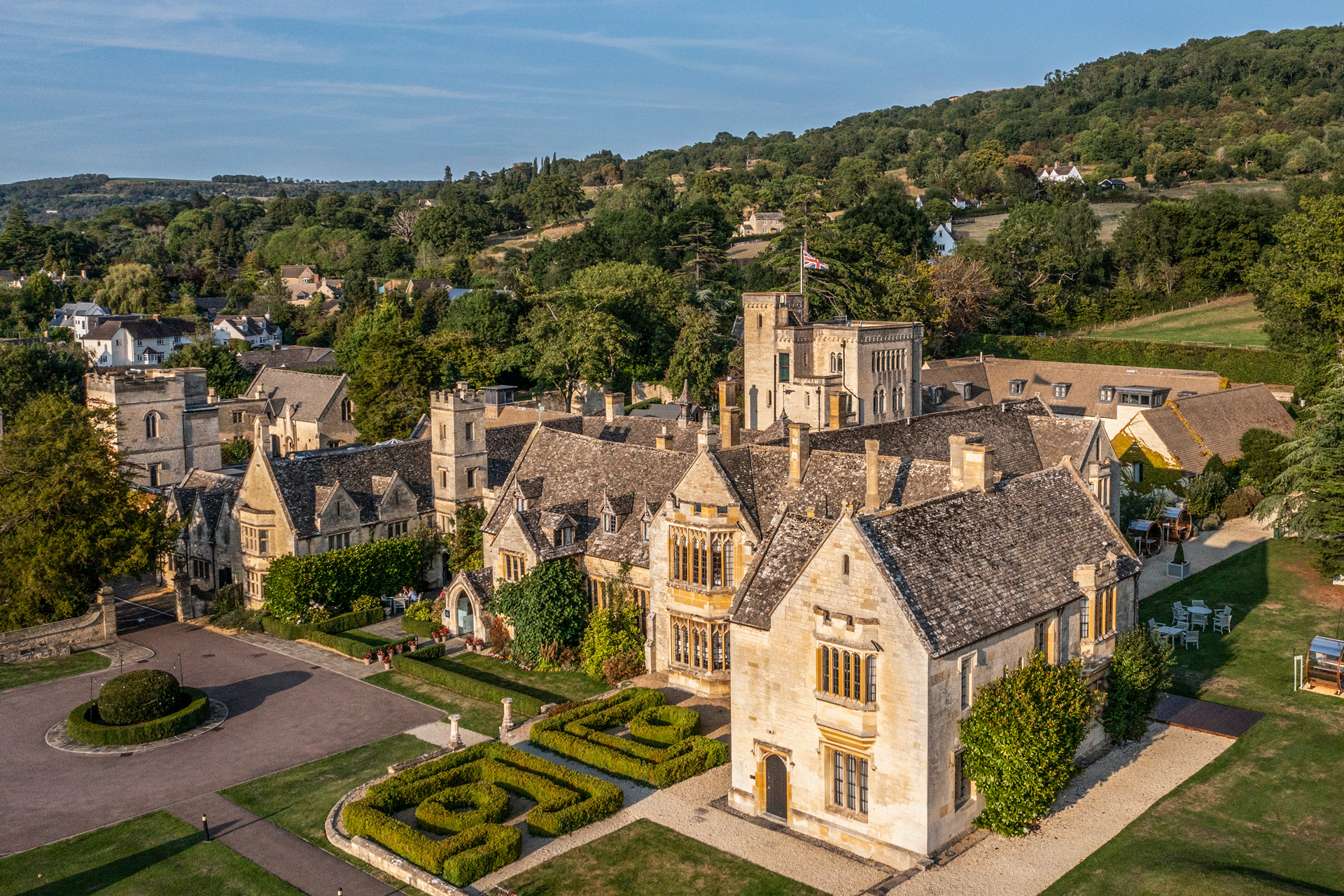 Sandstone buildings with fields surrounding and landscaped hedges in the foreground