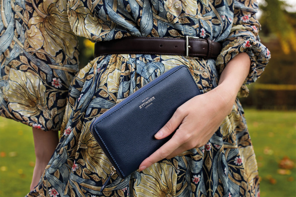 A close-up of a woman holding an Ettinger-branded clutch