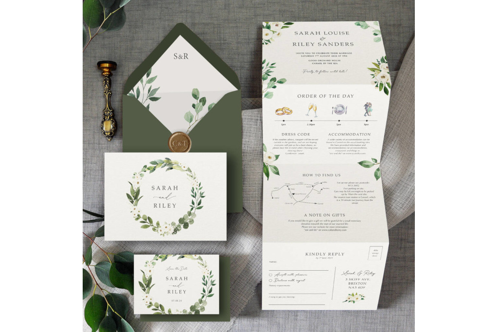 Green floral wedding invitations spread on grey surface