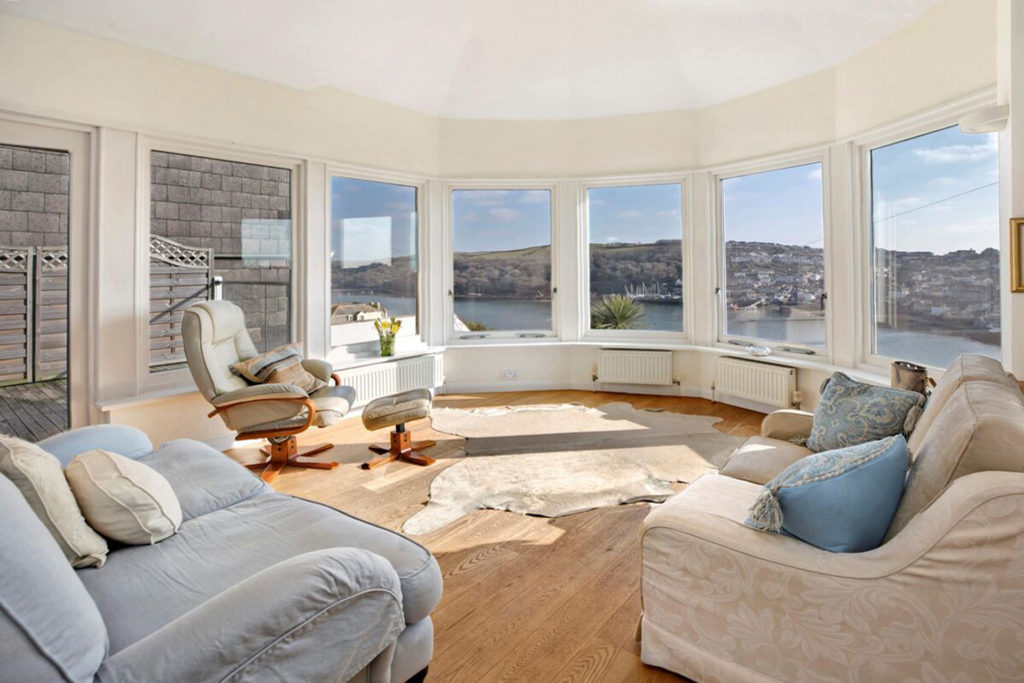 Living room with large bay windows looking onto the sea