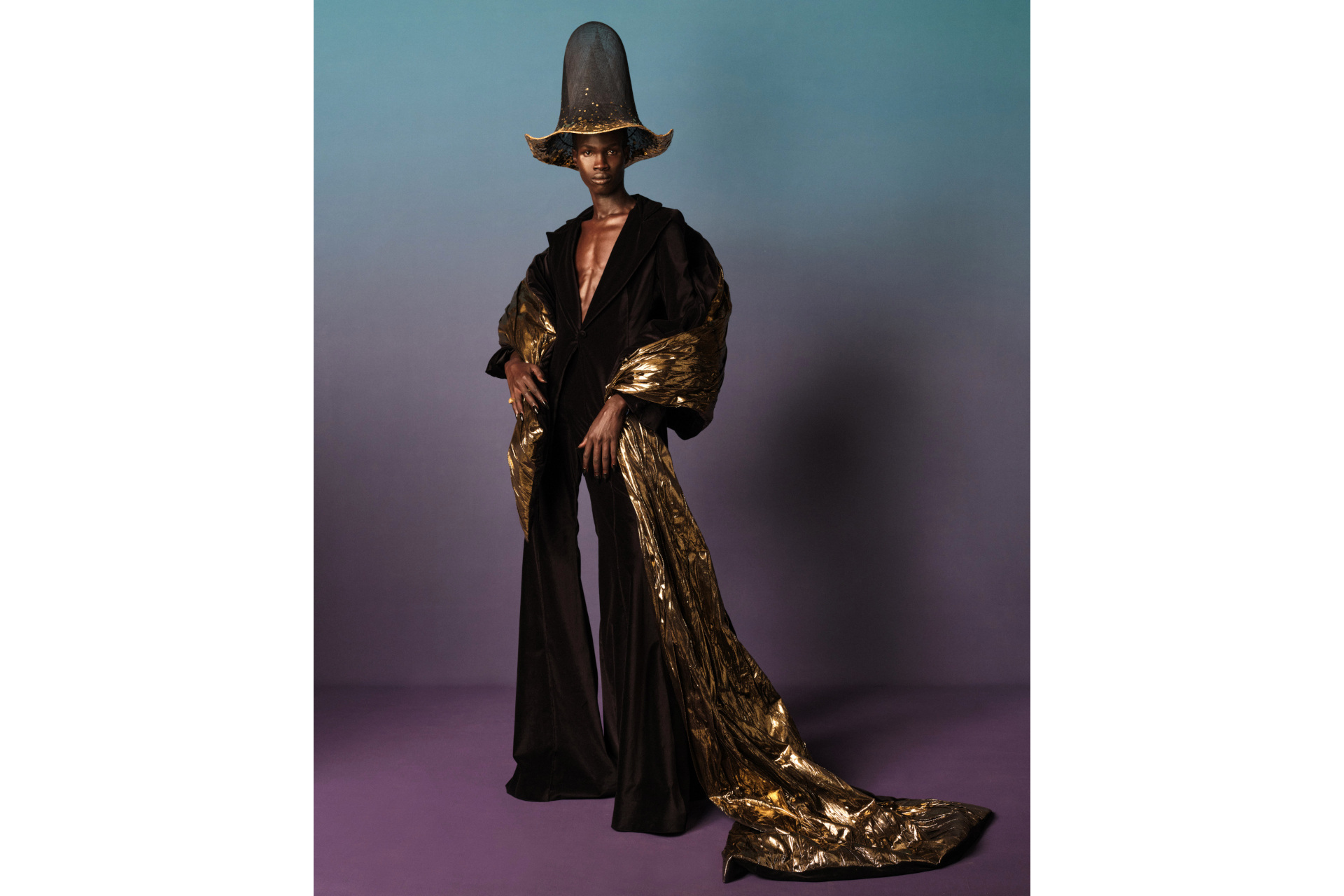 Black model in black and gold suit with tall hat