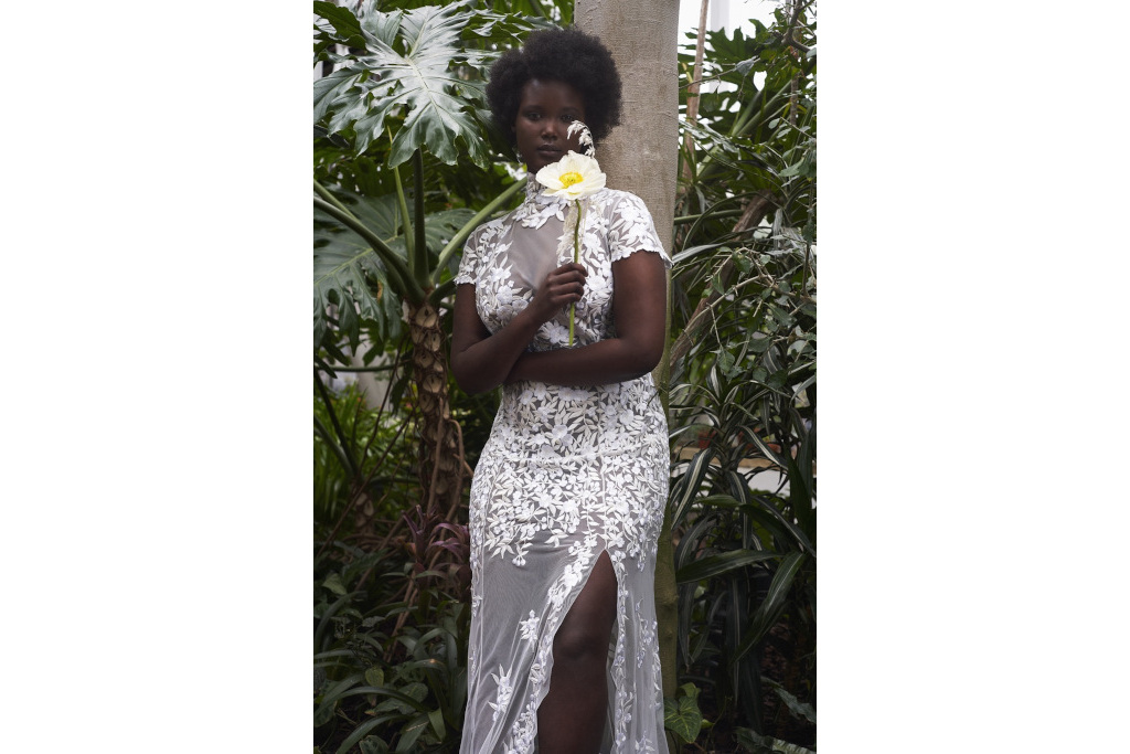 Black woman in sheer white dress holding flower
