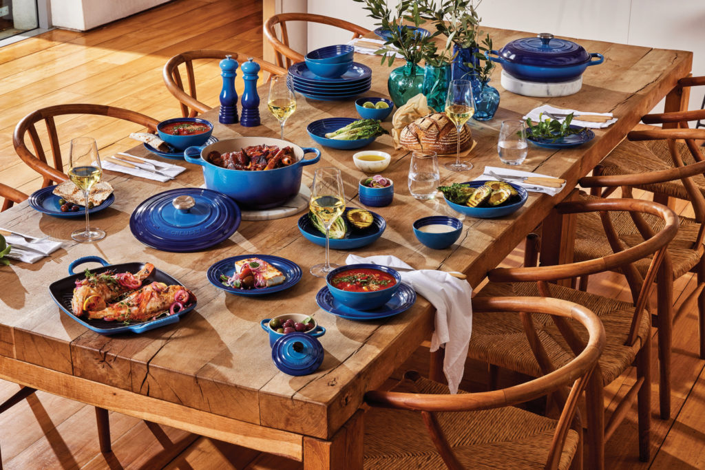 Wooden table laid with blue pots and crockery