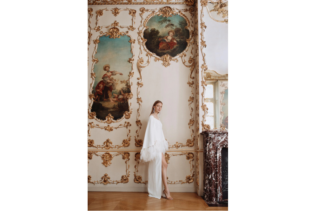 Woman in ornately decorated room wearing long white dress