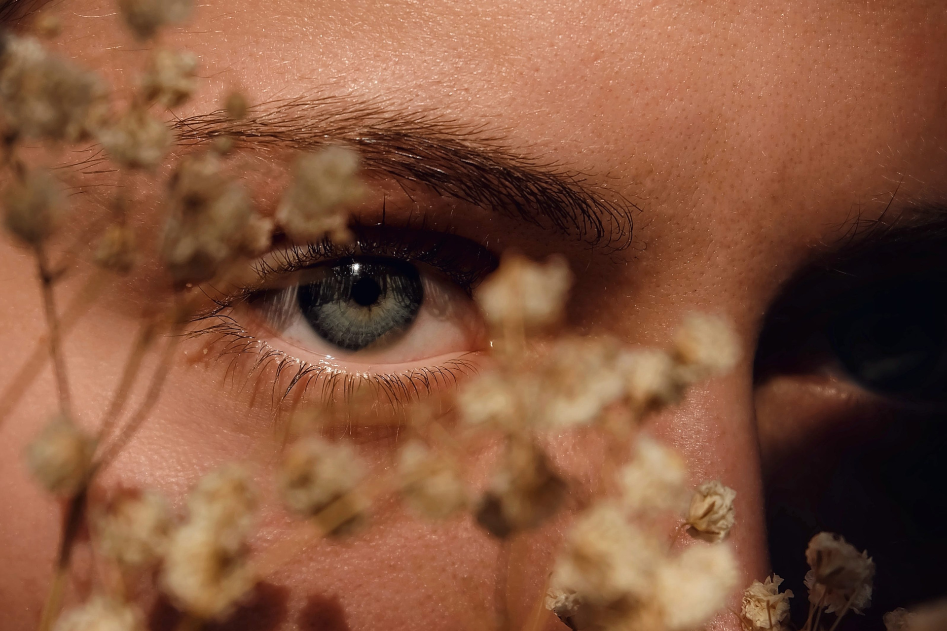 Close up of woman's eye with small flowers held in front