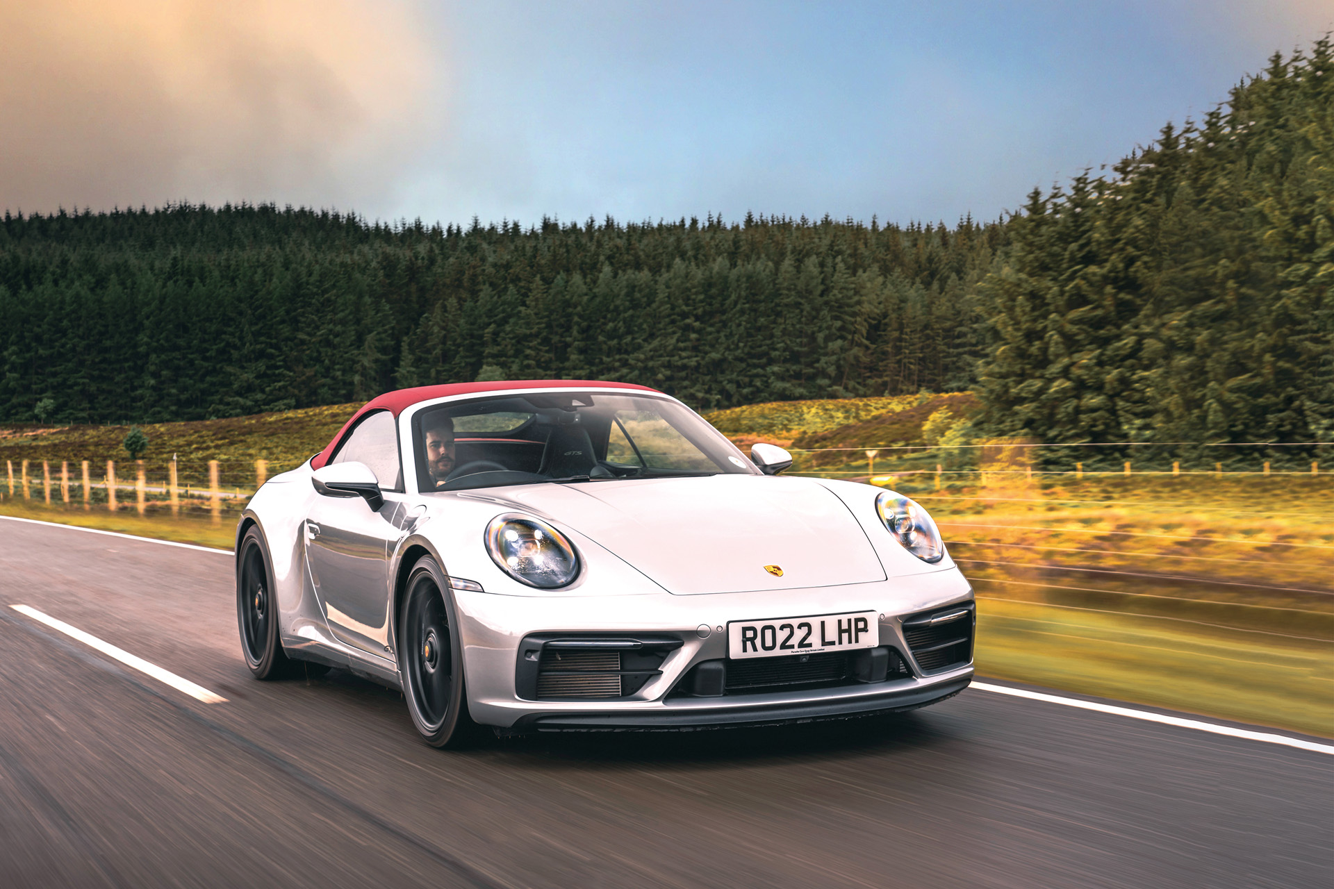 The Porsche 911 Cabriolet on a road with a forest in the background