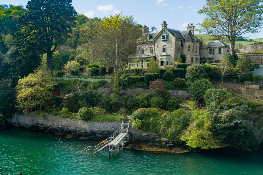 House sitting on the waterfront with greenery surrounding