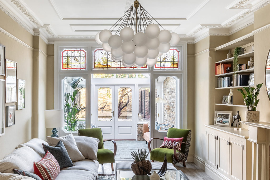 Living room featuring toffee-coloured walls, a beige sofa, and a statement light feature with spherical lamps.