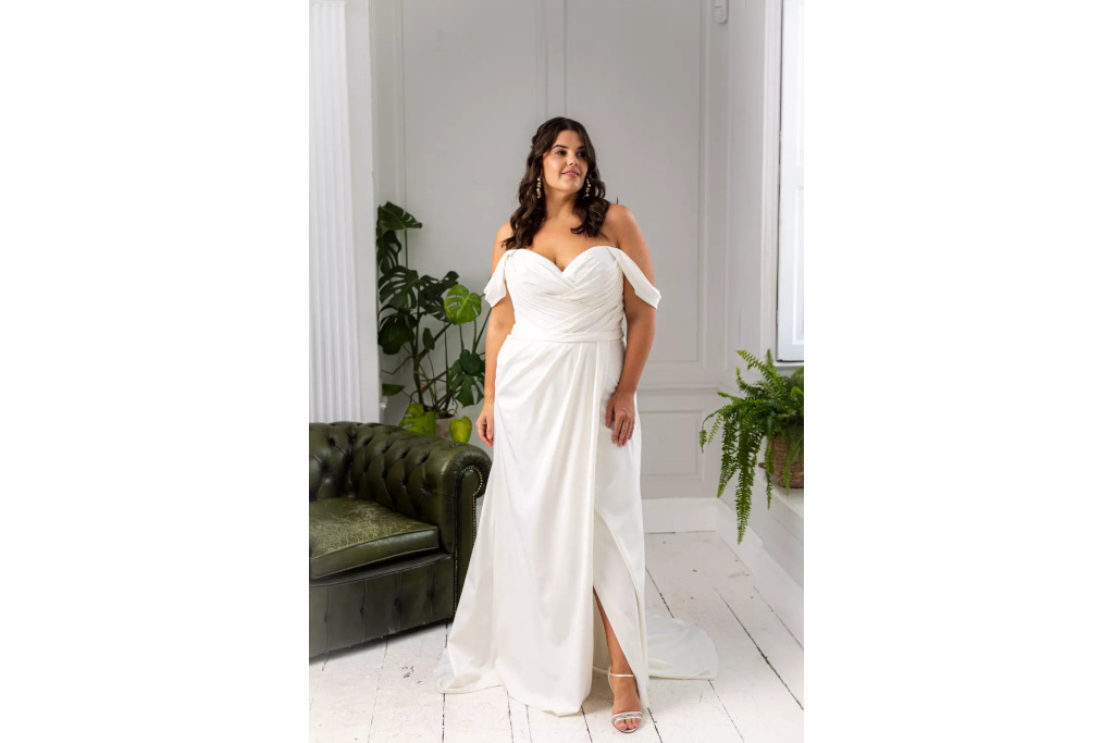 Woman in white dress in white room by green armchair